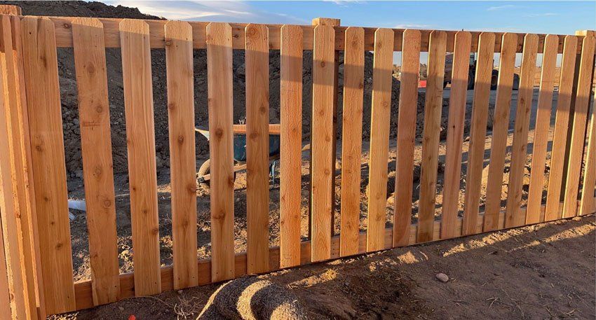 A wooden fence is sitting on top of a dirt field.