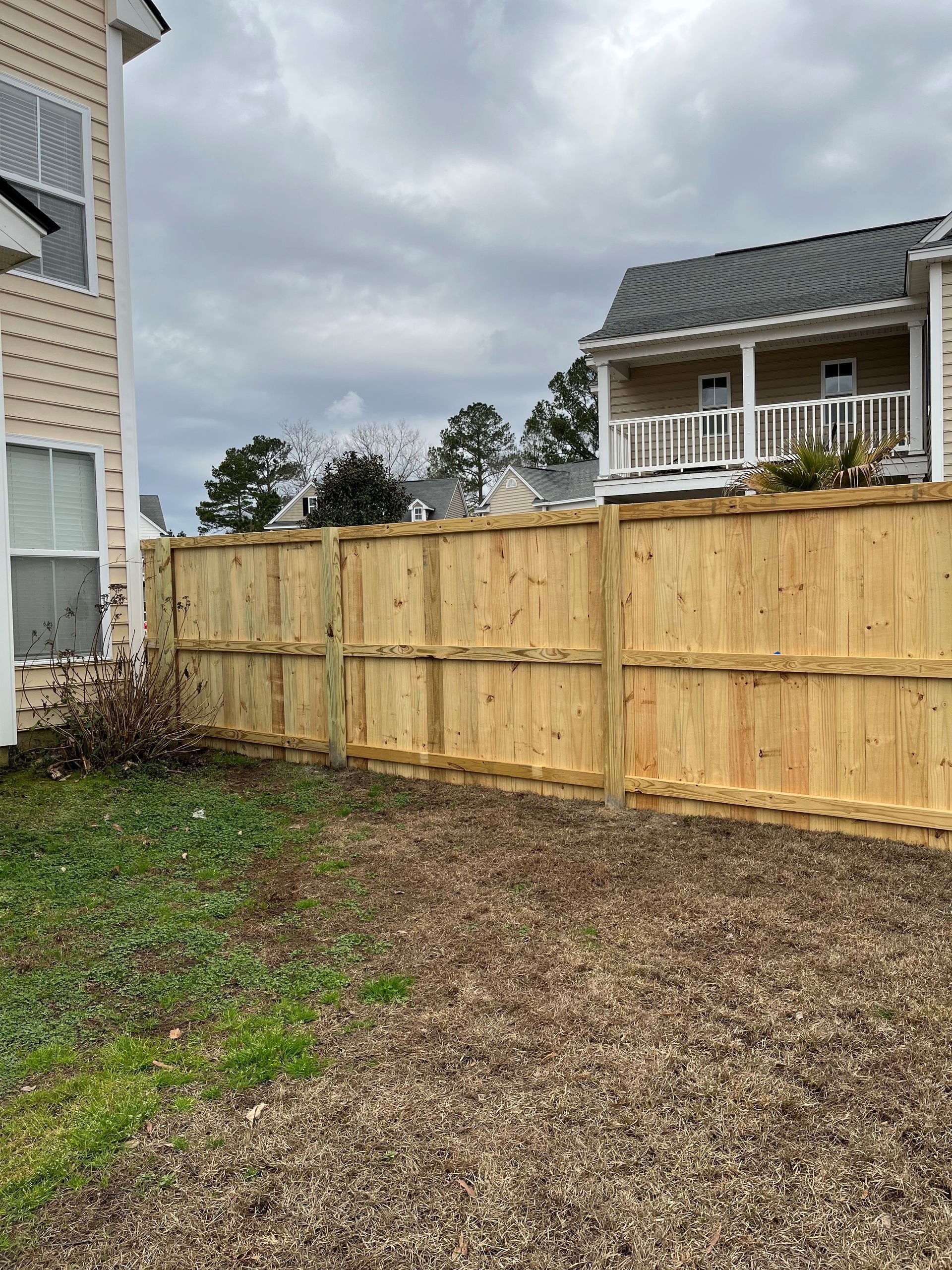 A wooden fence is in the backyard of a house.