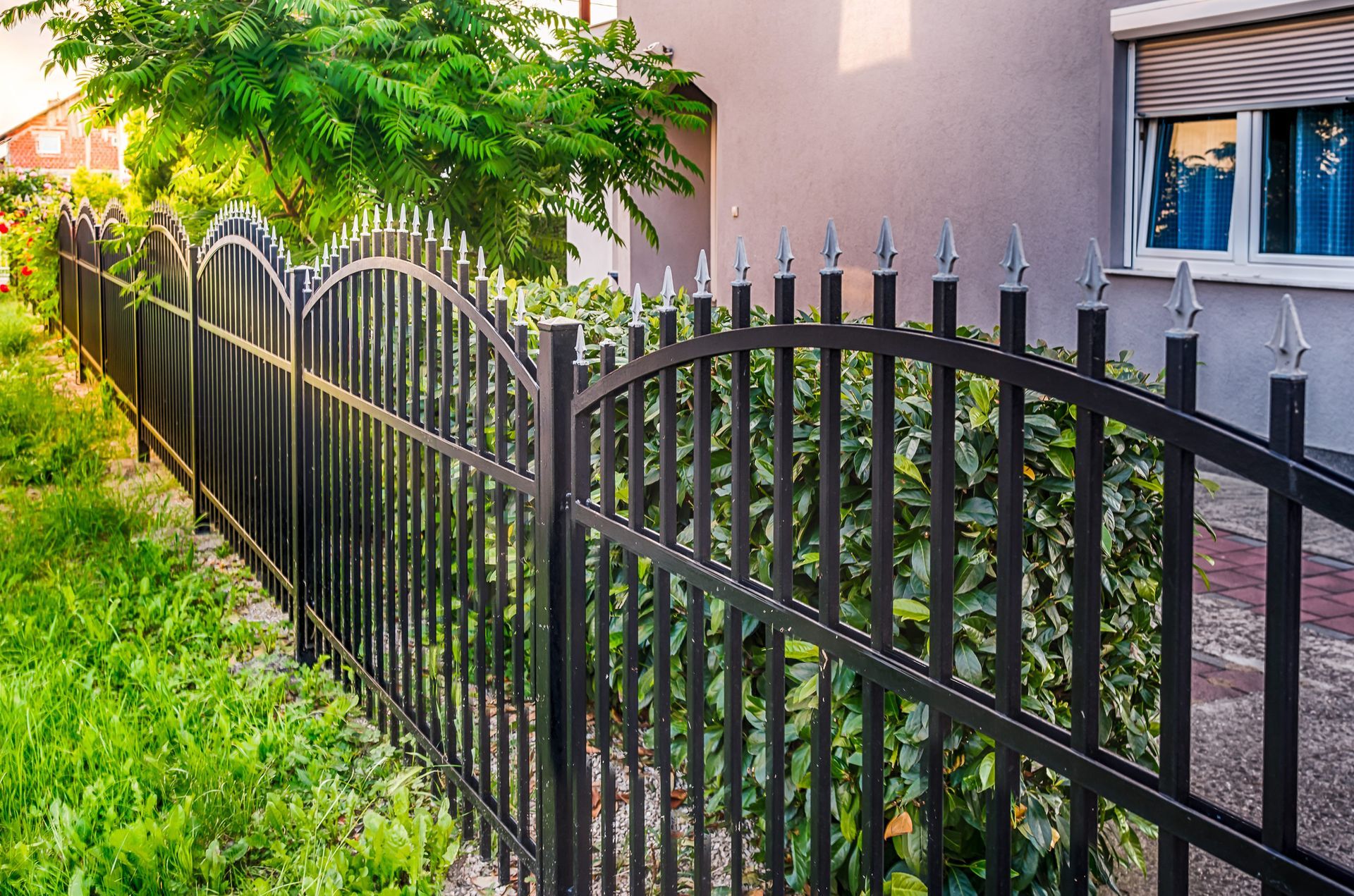 A black wrought iron fence is in front of a house.