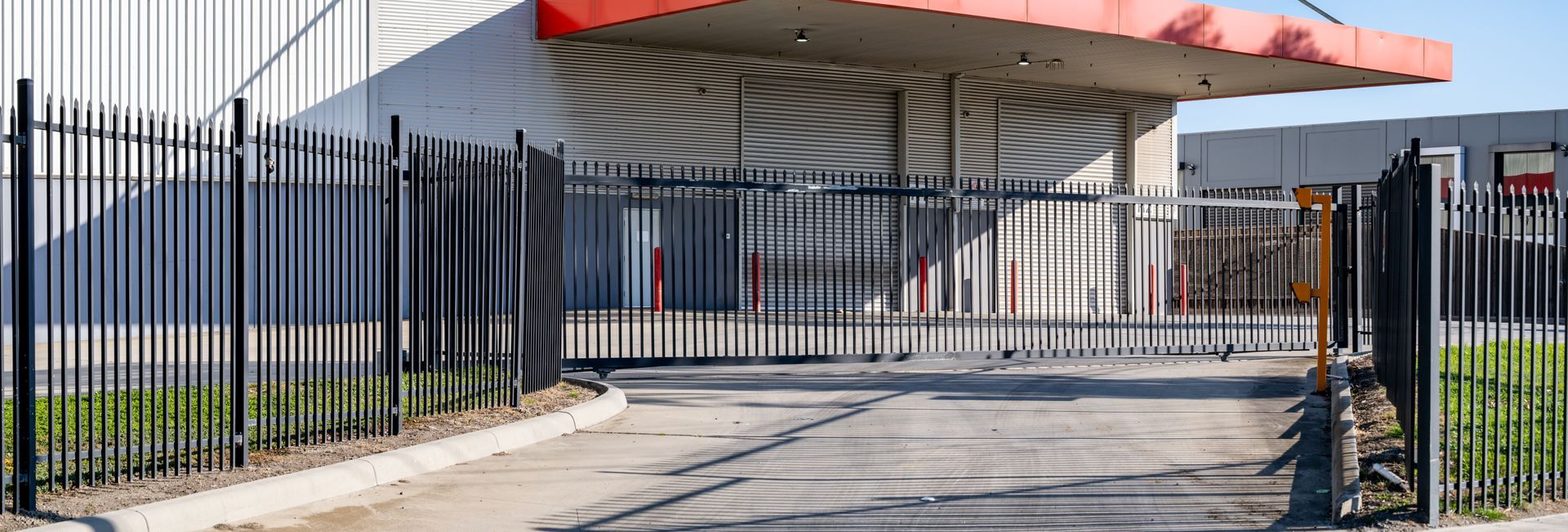 Industrial building entrance with metal security fence and closed gate driveway. Industrial building entrance with metal security fence and closed gate driveway.
