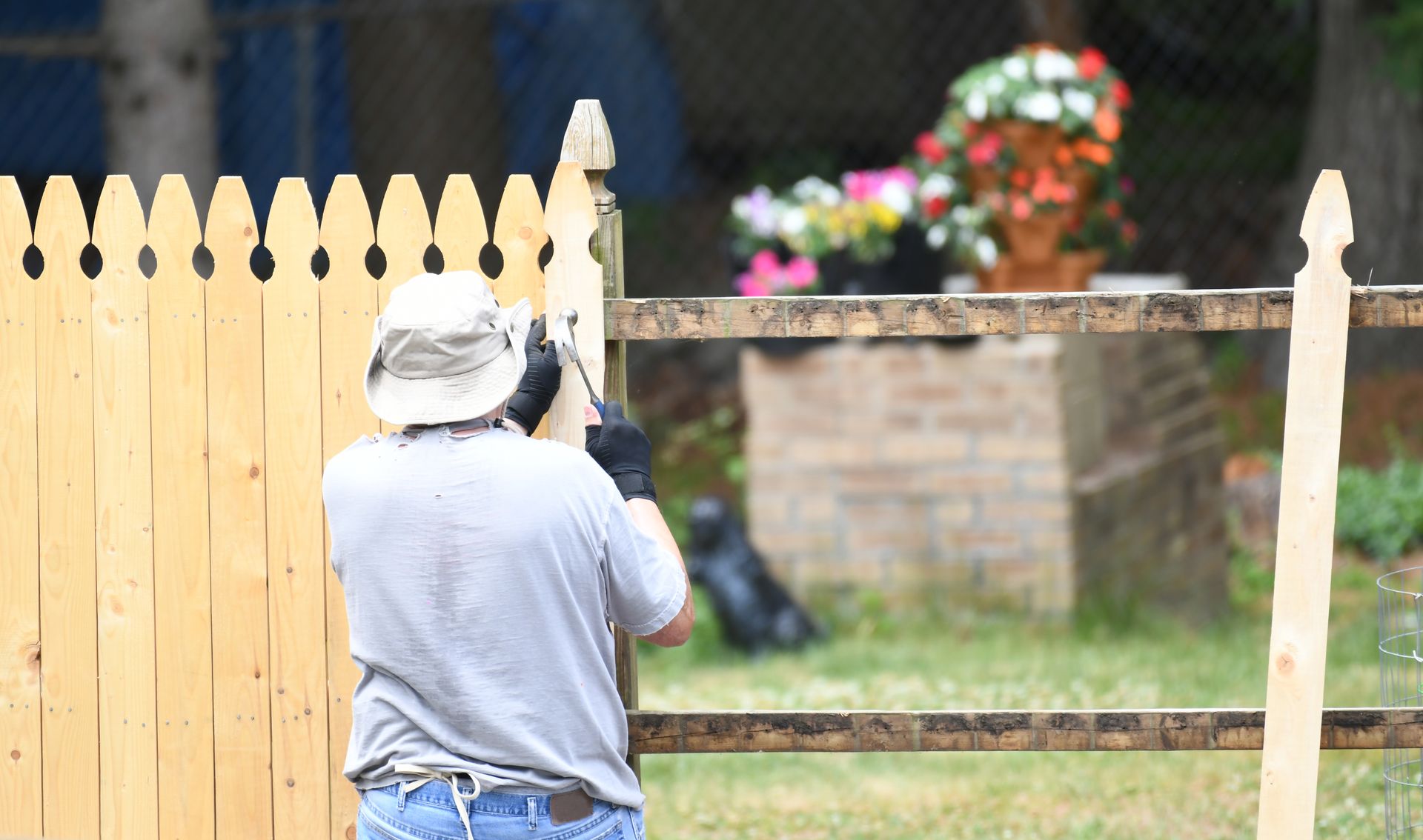 Worker aligning and securing wooden fence panels during a fence installation