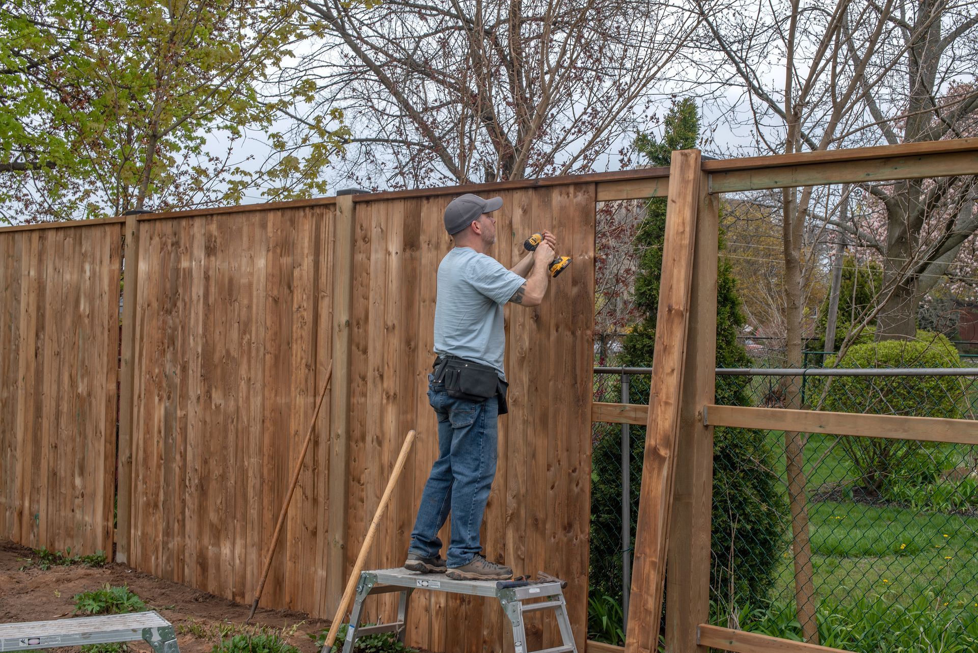 A man is installing a wood fence.