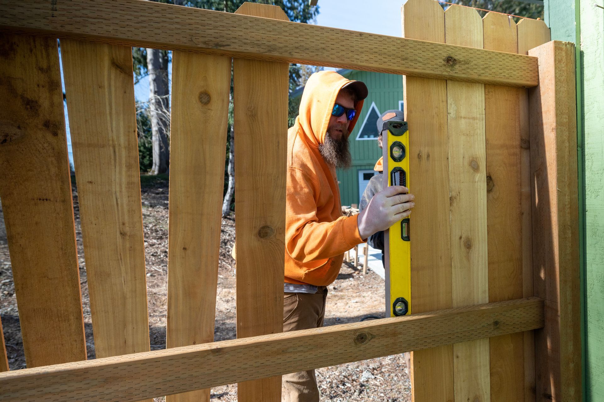 A man is measuring a wood fence for leveling. A man is measuring a wood fence for leveling.