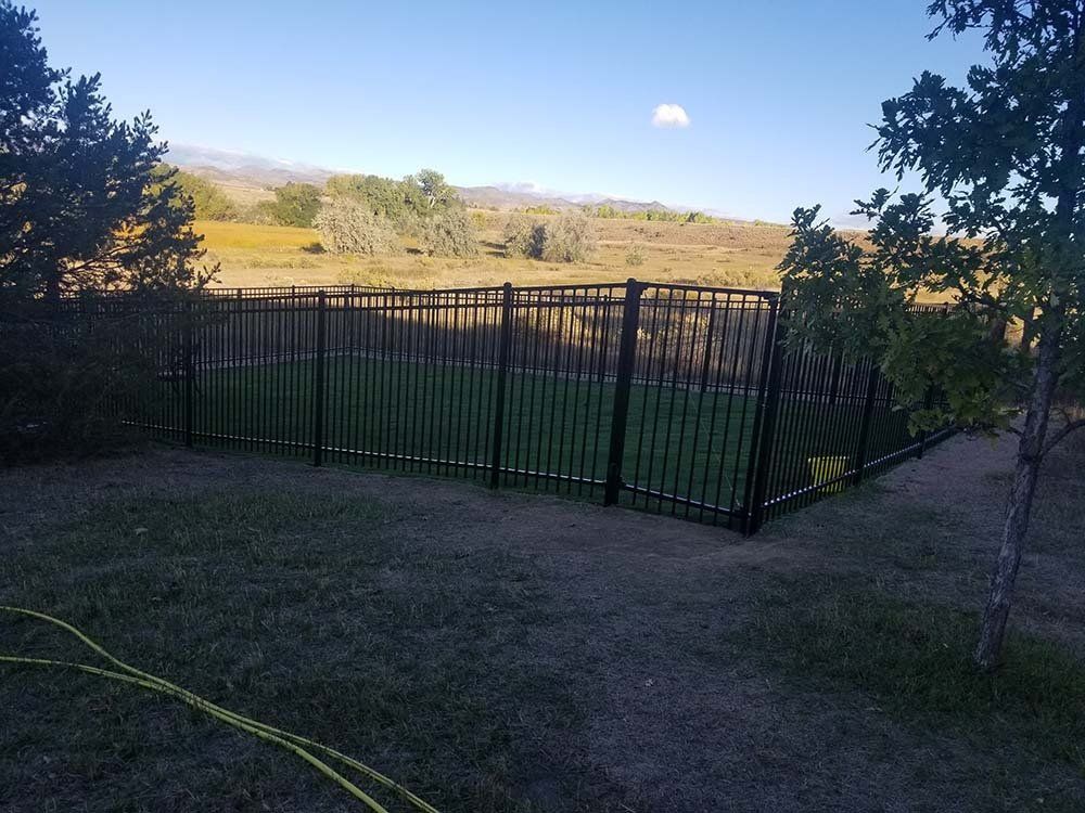 A metal fence surrounds a soccer field in the middle of a field.