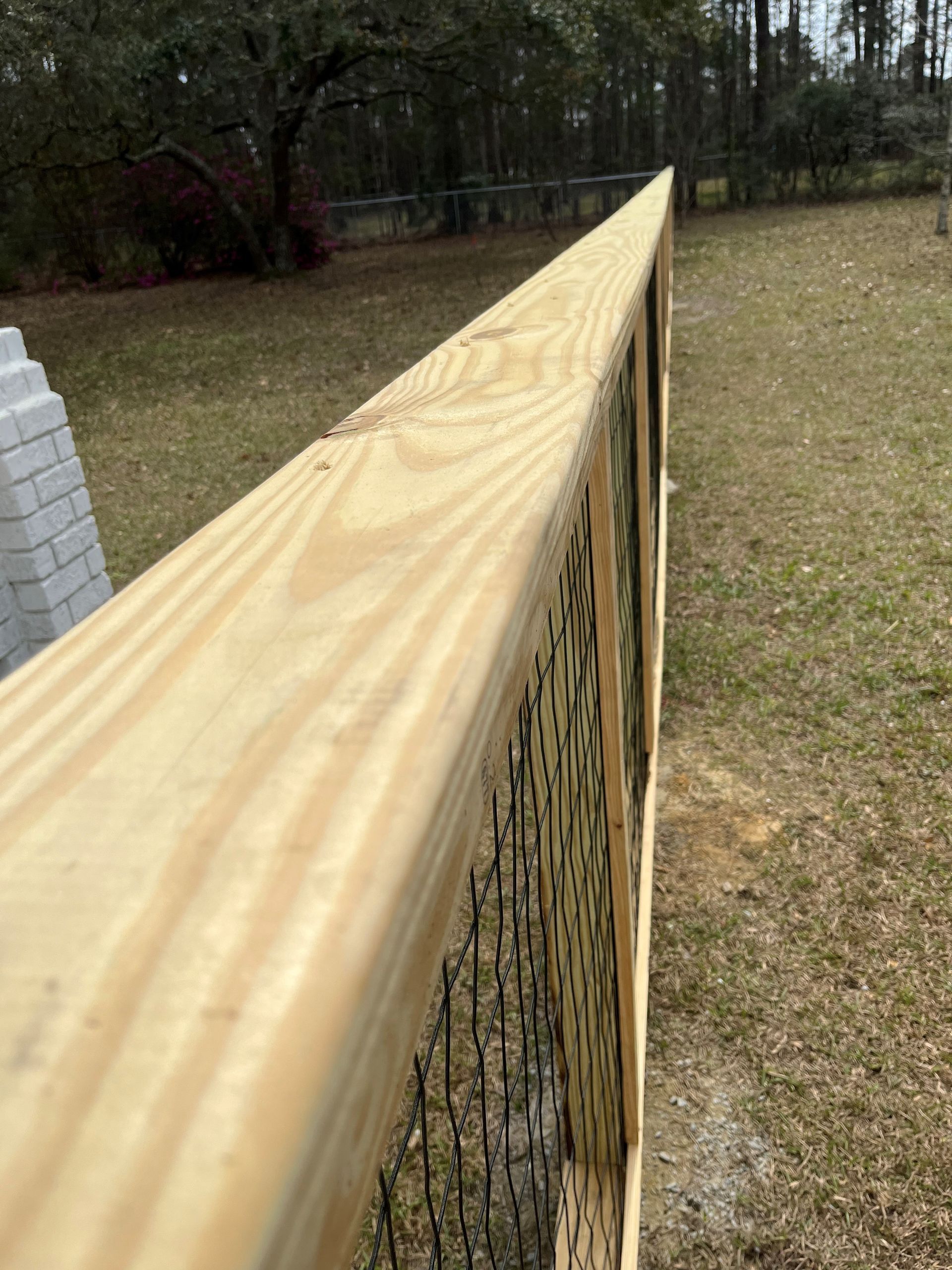 A close up of a wooden fence with chicken wire.