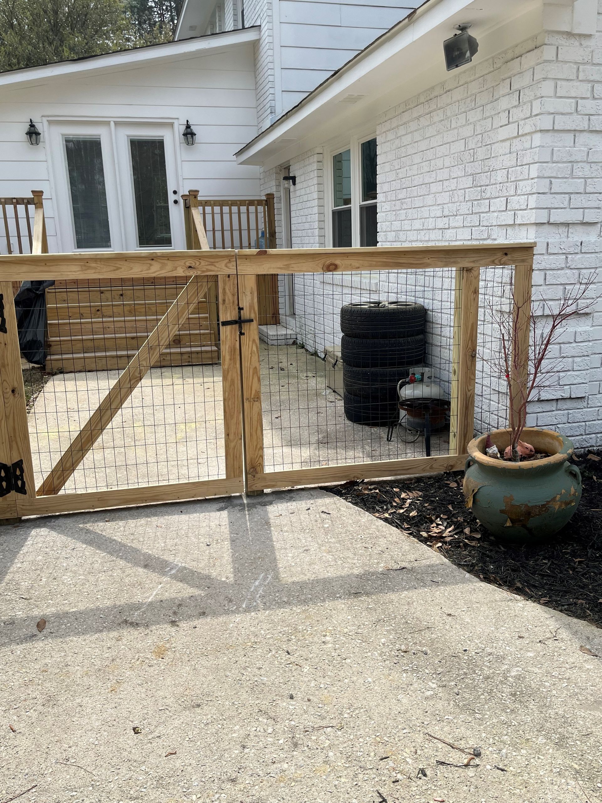 A wooden gate is sitting in front of a white brick house.