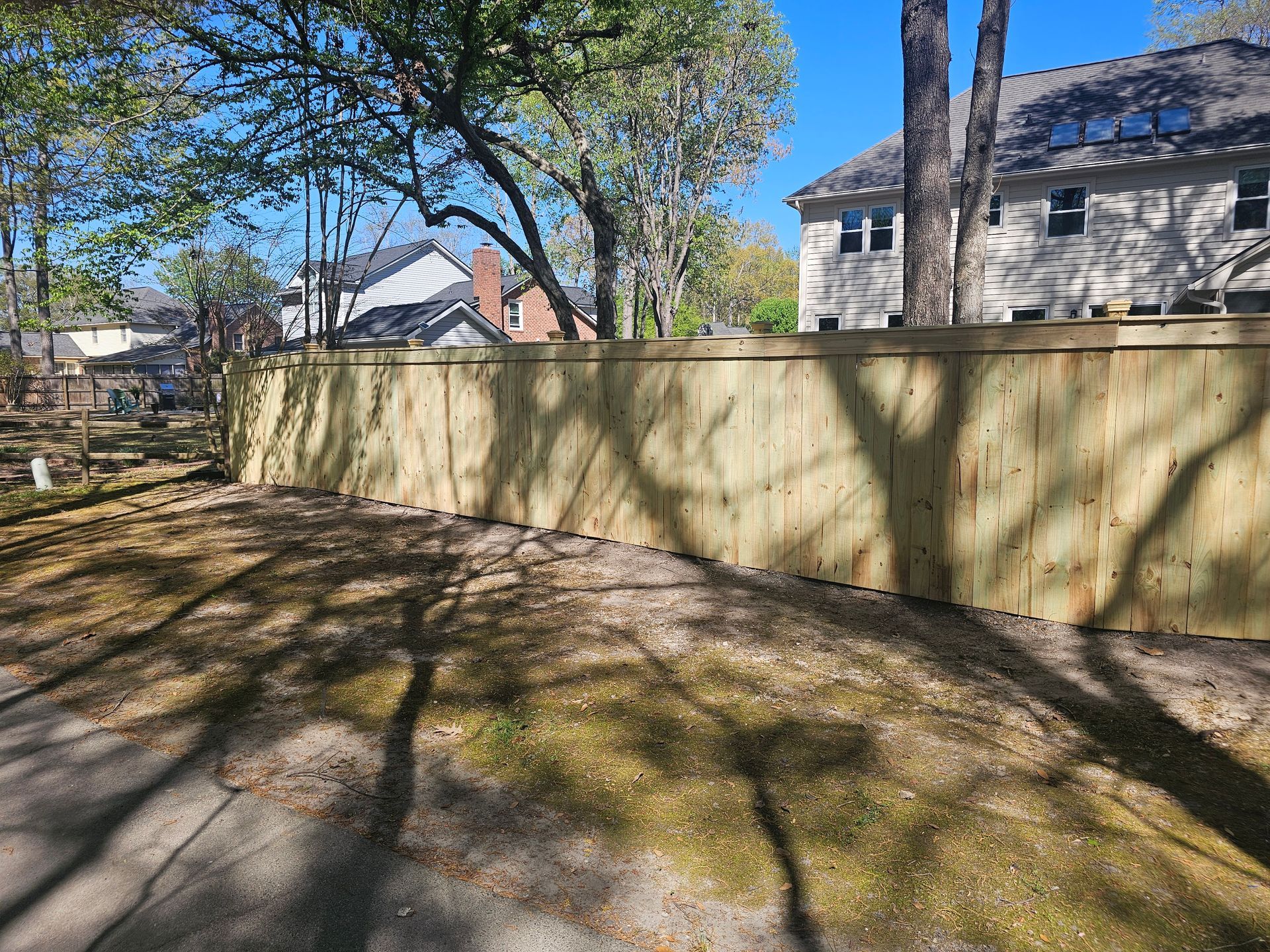A wooden fence is surrounded by trees in a backyard.