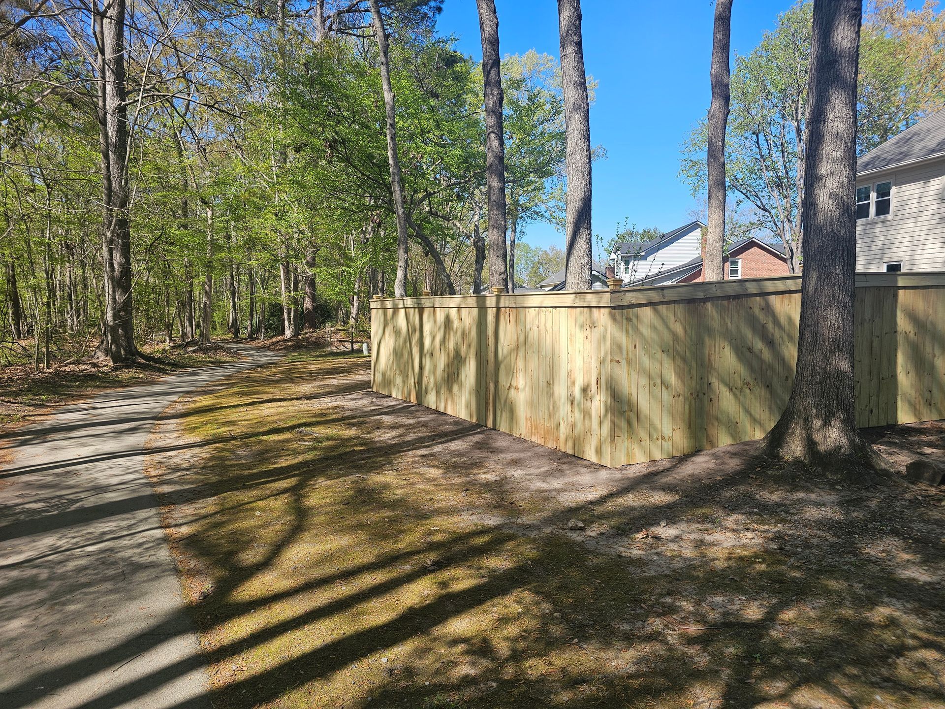 A wooden fence is surrounded by trees on the side of a road.