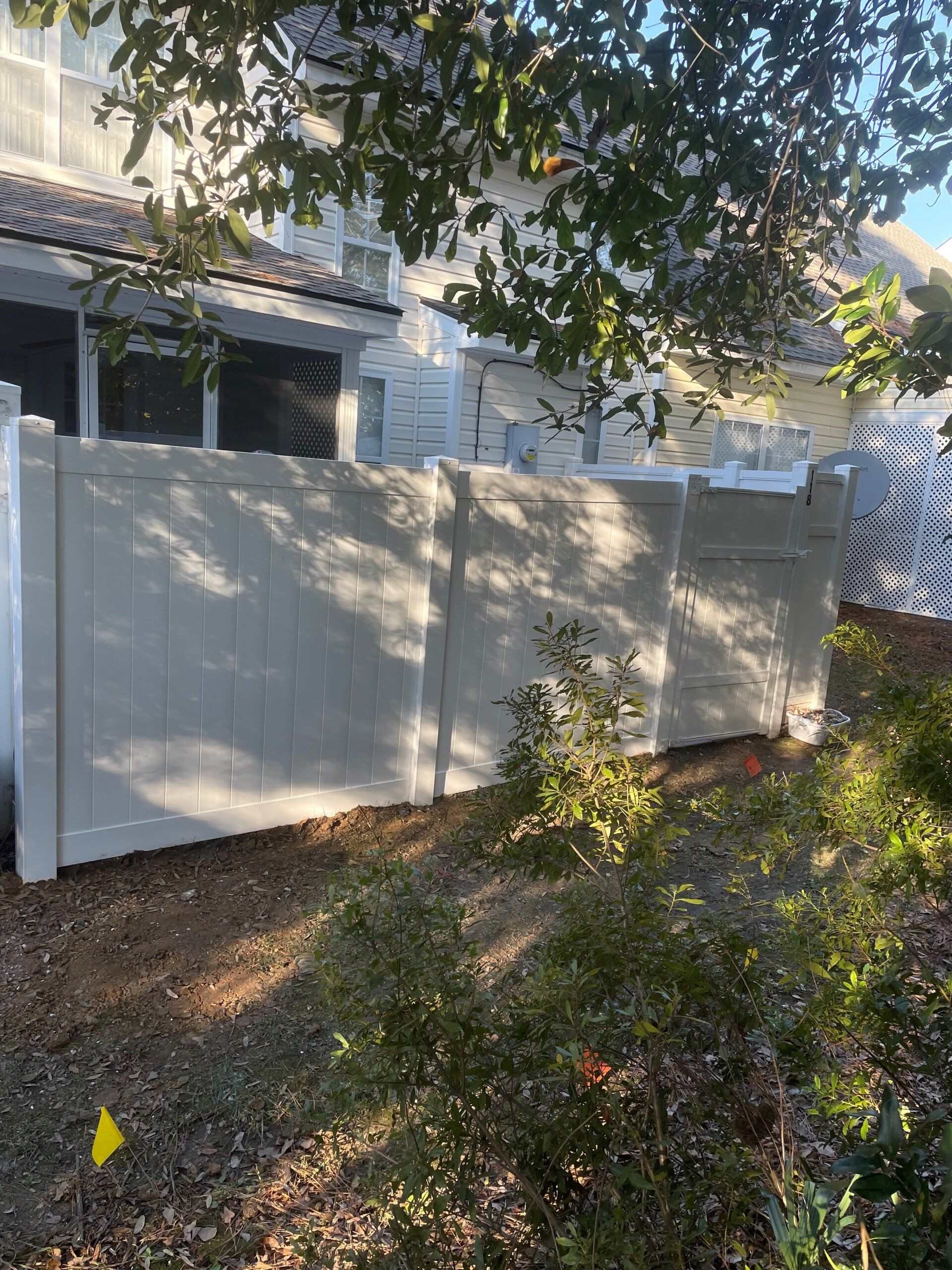 A white fence is in the backyard of a house.