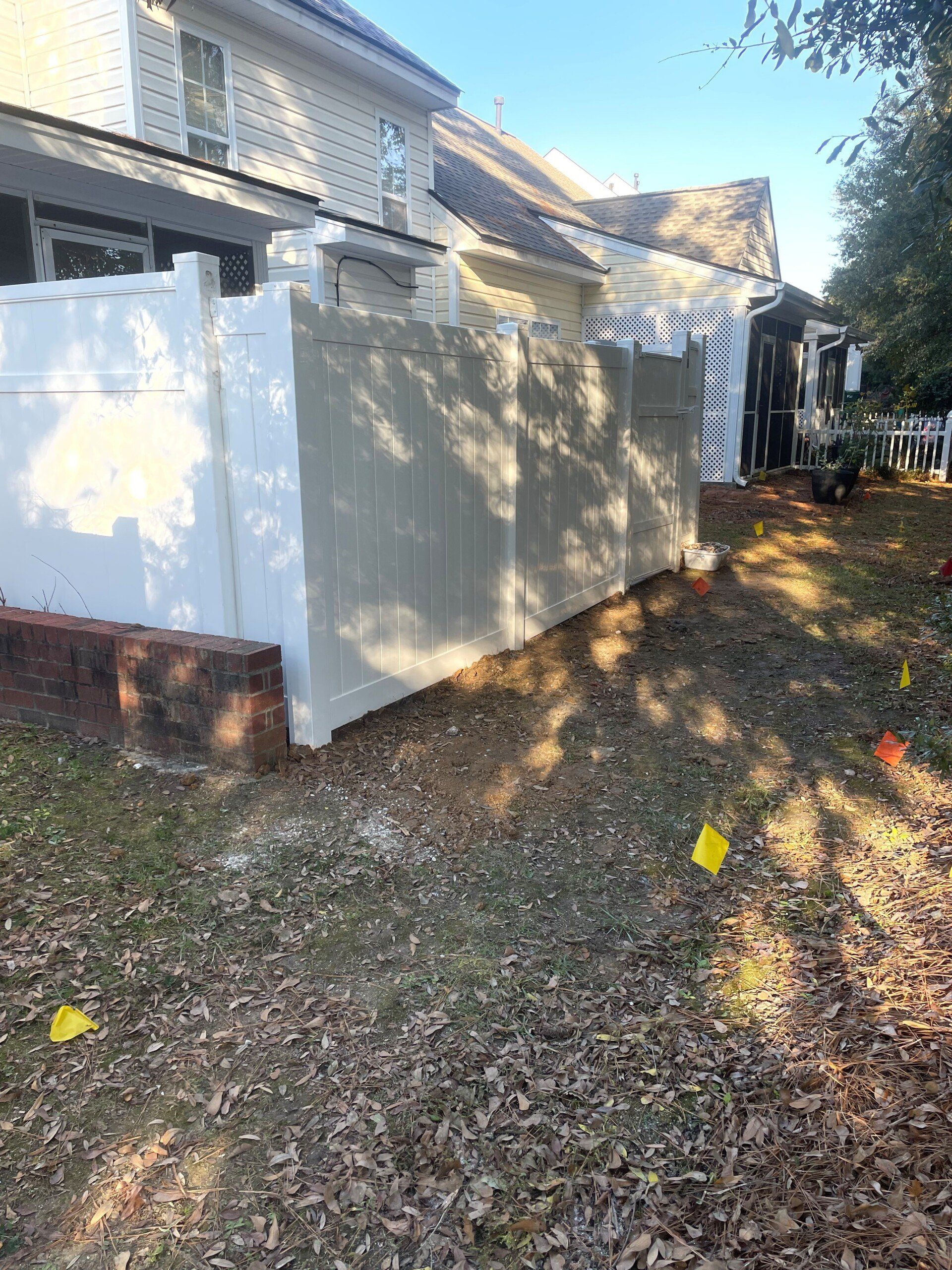 A white fence is in the backyard of a house.
