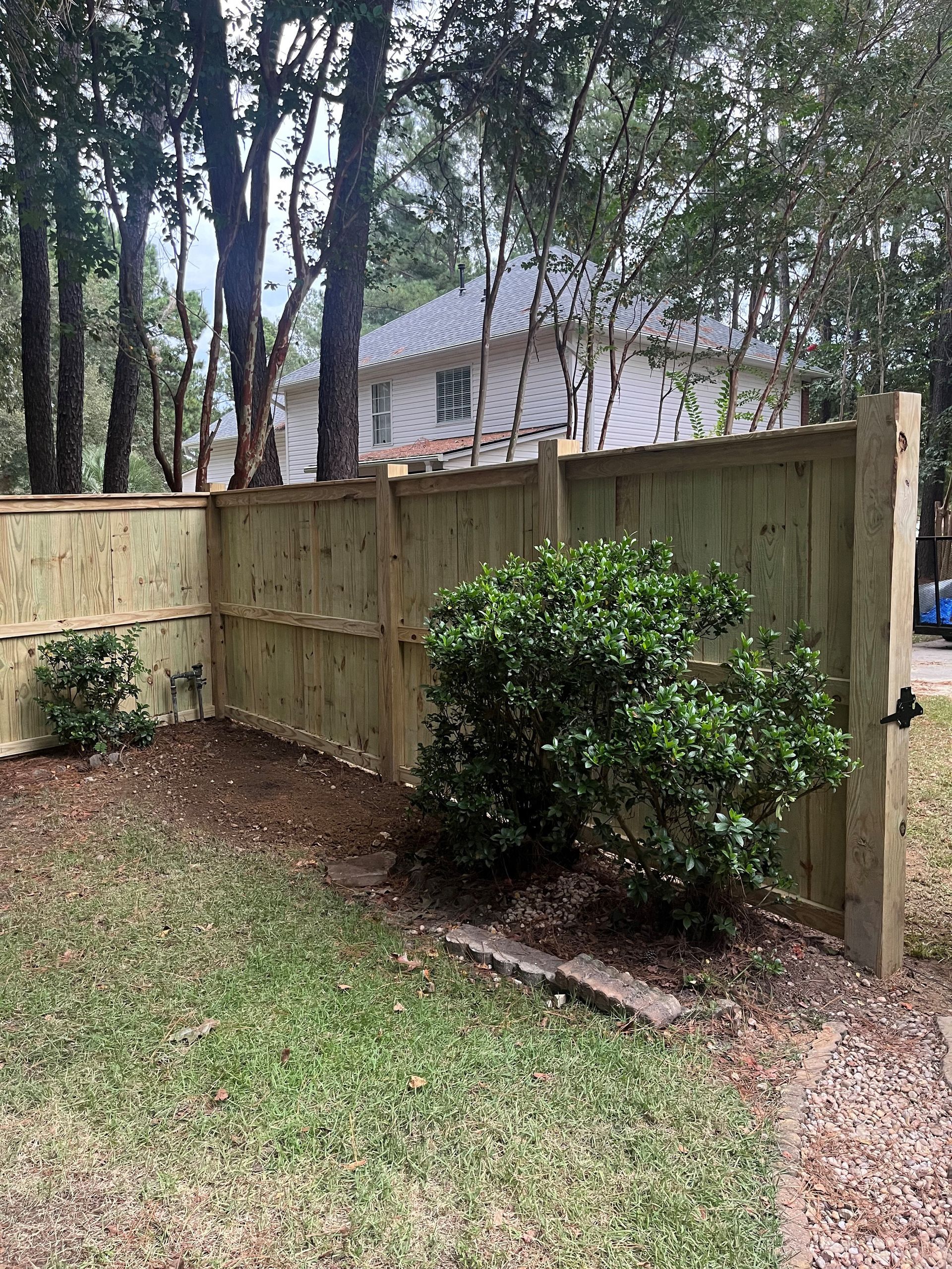 A wooden fence is in the backyard of a house.