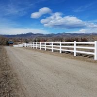 A white fence along the side of a dirt road.