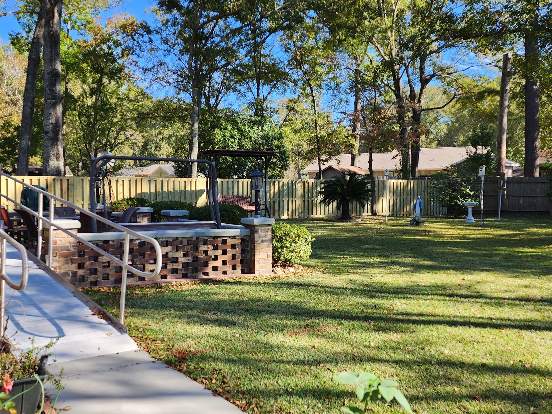 A lush green yard with a fence and a walkway