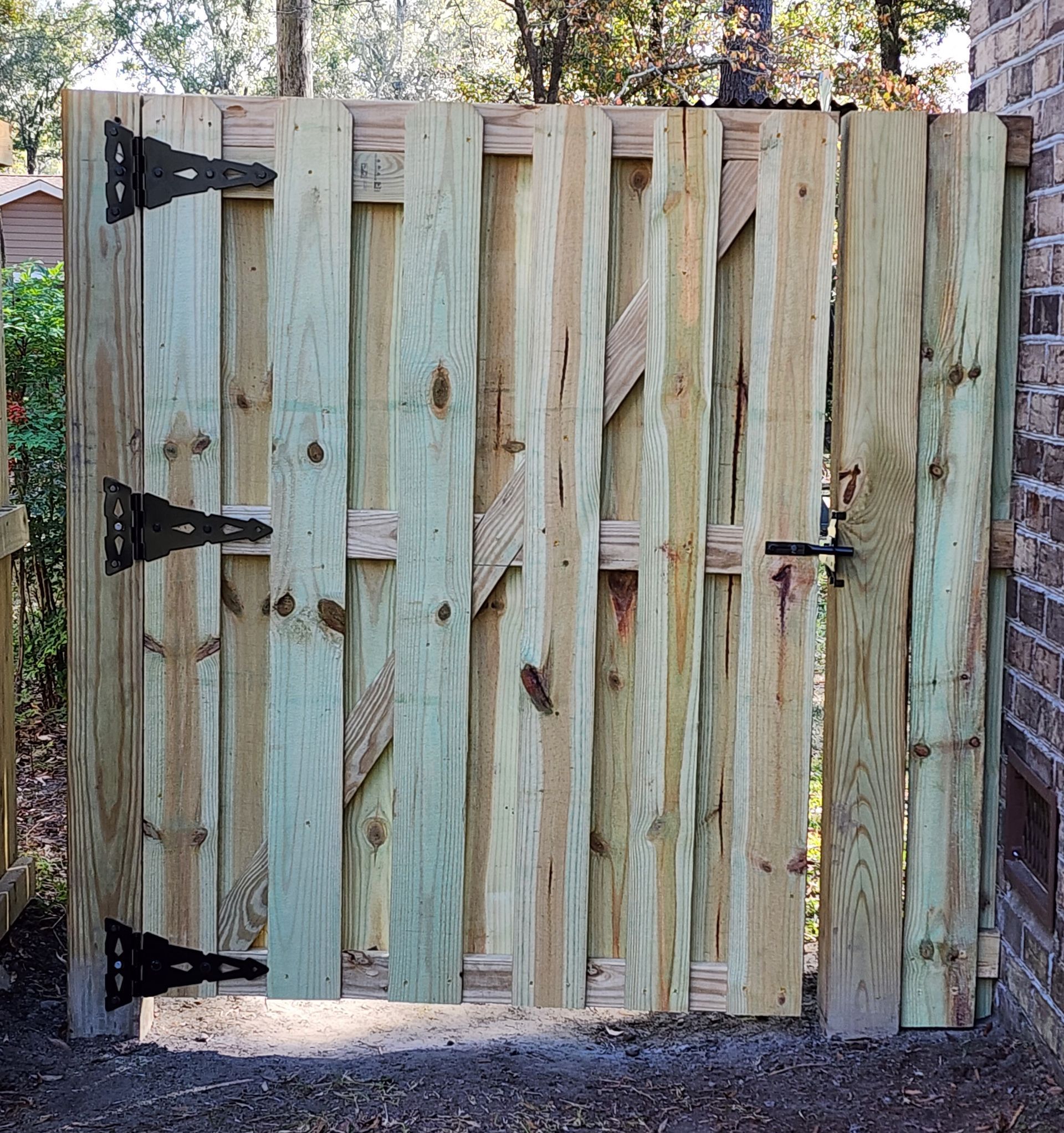 A wooden gate with a brick wall in the background