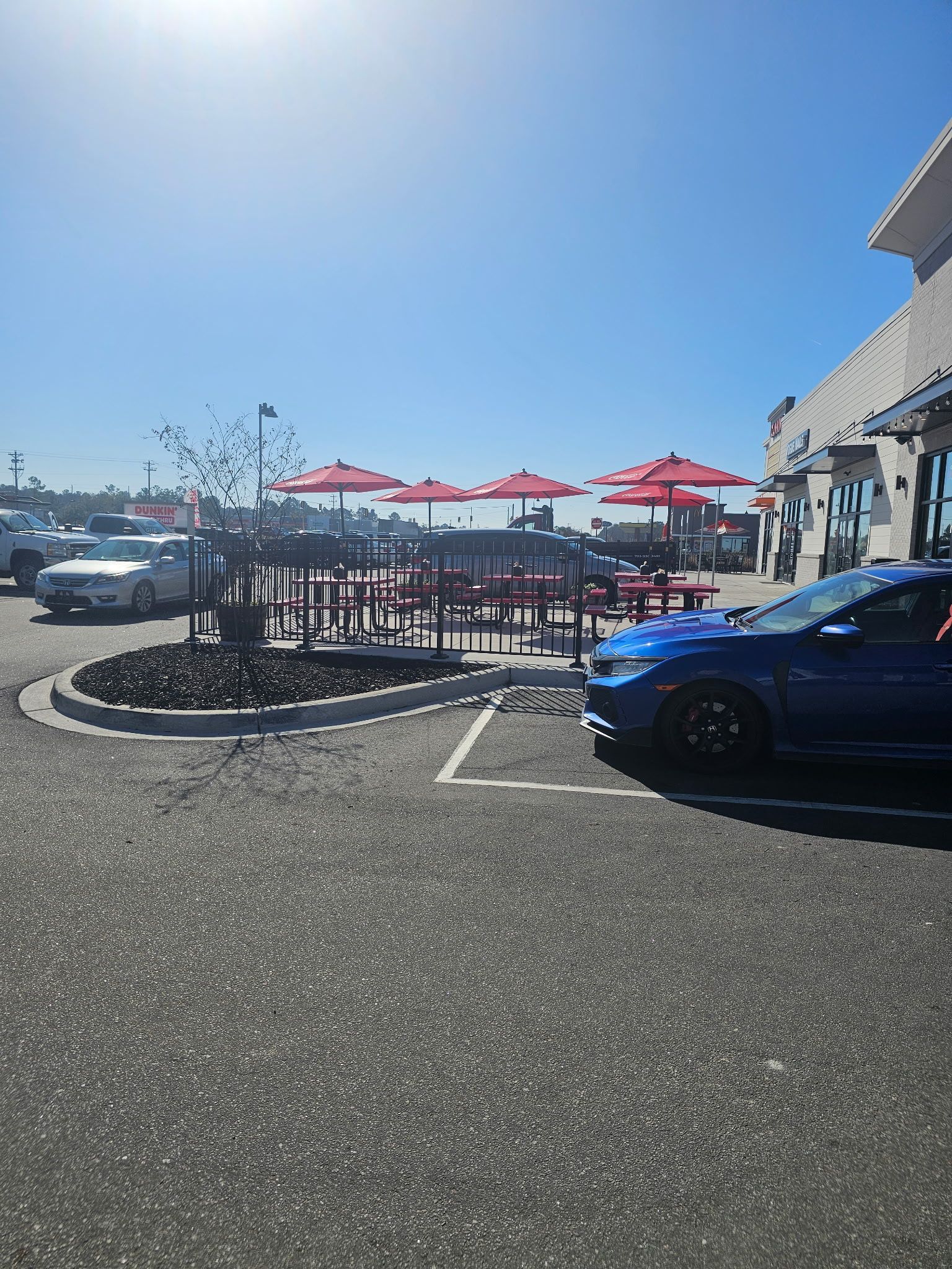 A blue car is parked in a parking lot in front of a restaurant.