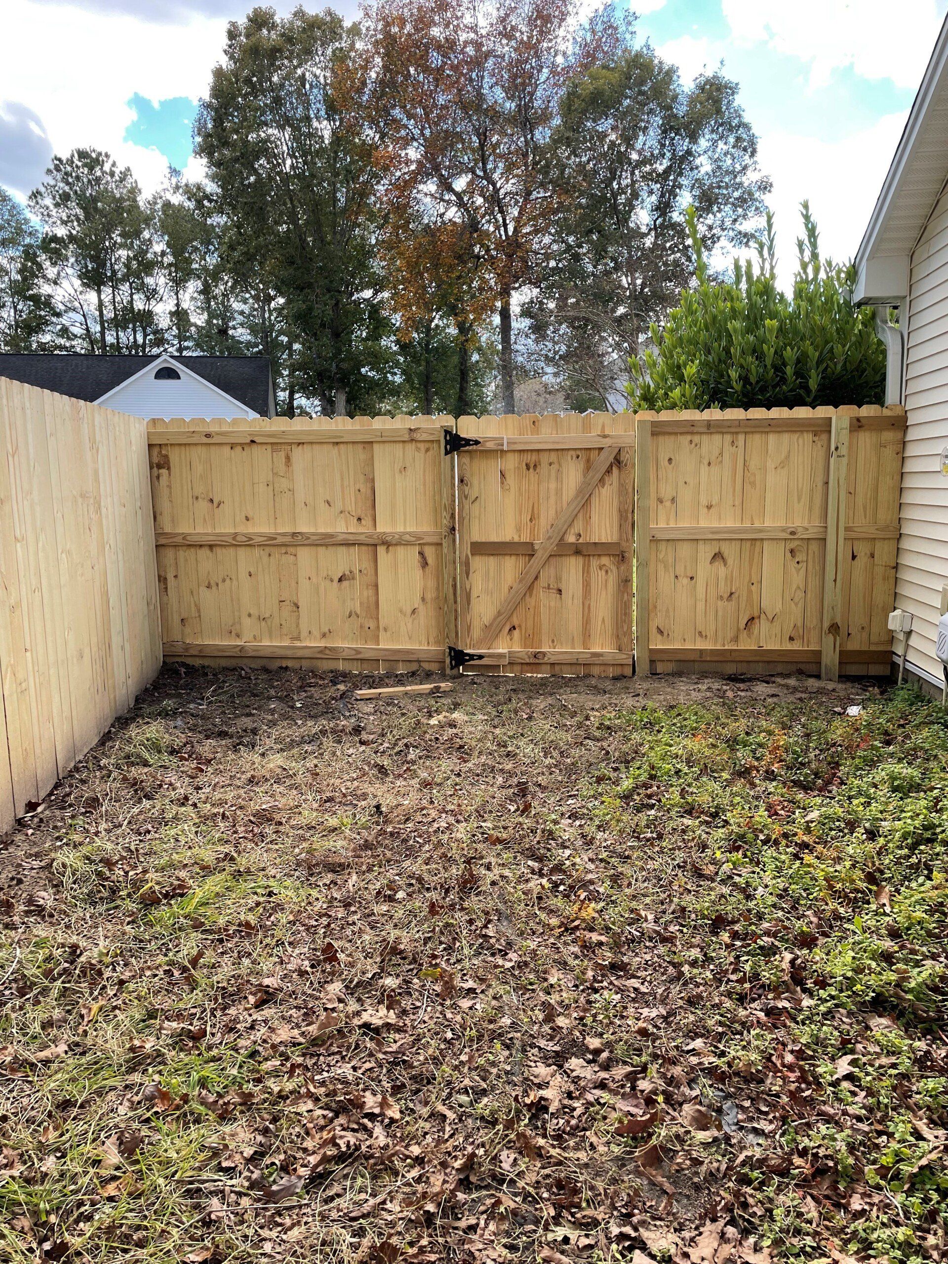 A wooden fence with a gate in the backyard of a house.