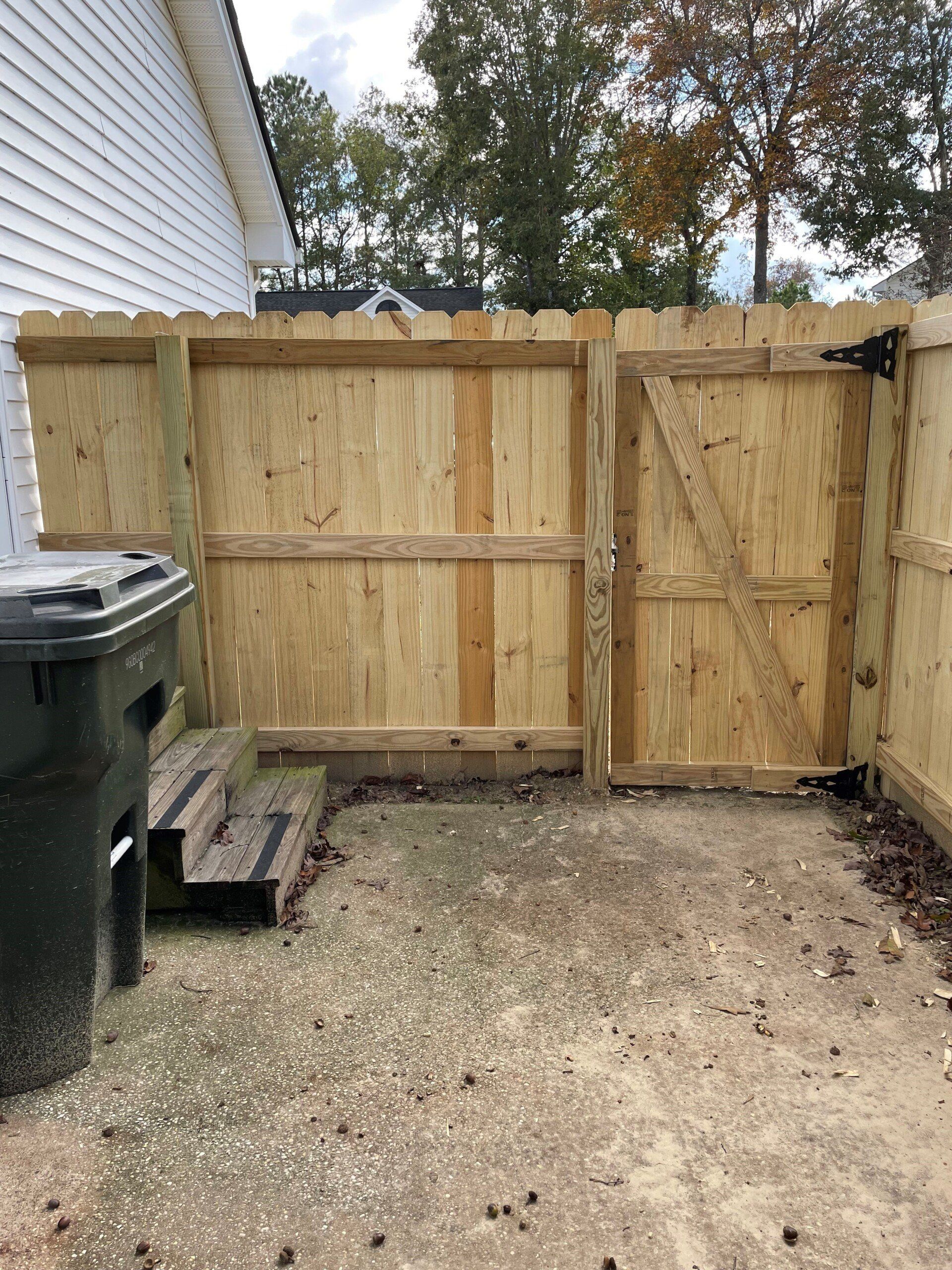 A wooden fence with a gate in the backyard of a house.