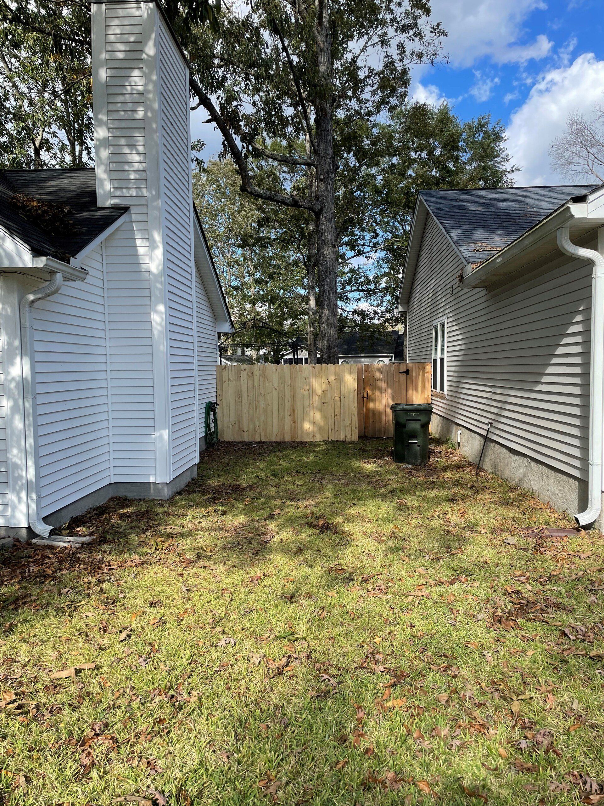 The backyard of a house with a wooden fence and a chimney.