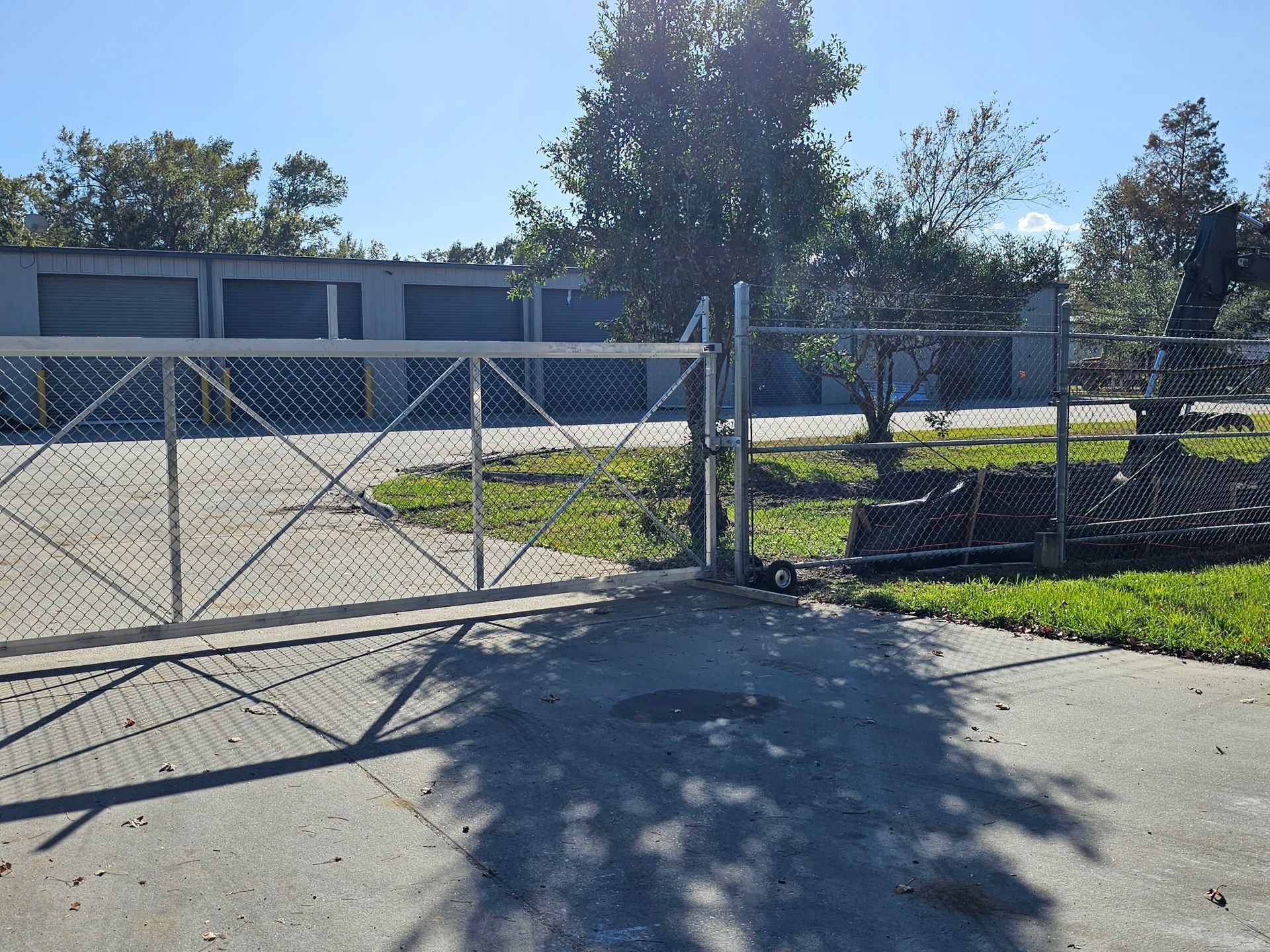 A chain link fence surrounds a parking lot with a building in the background.