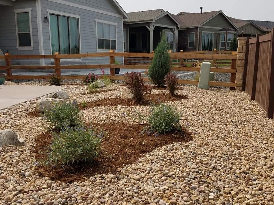 A gravel yard with a wooden fence in front of a house