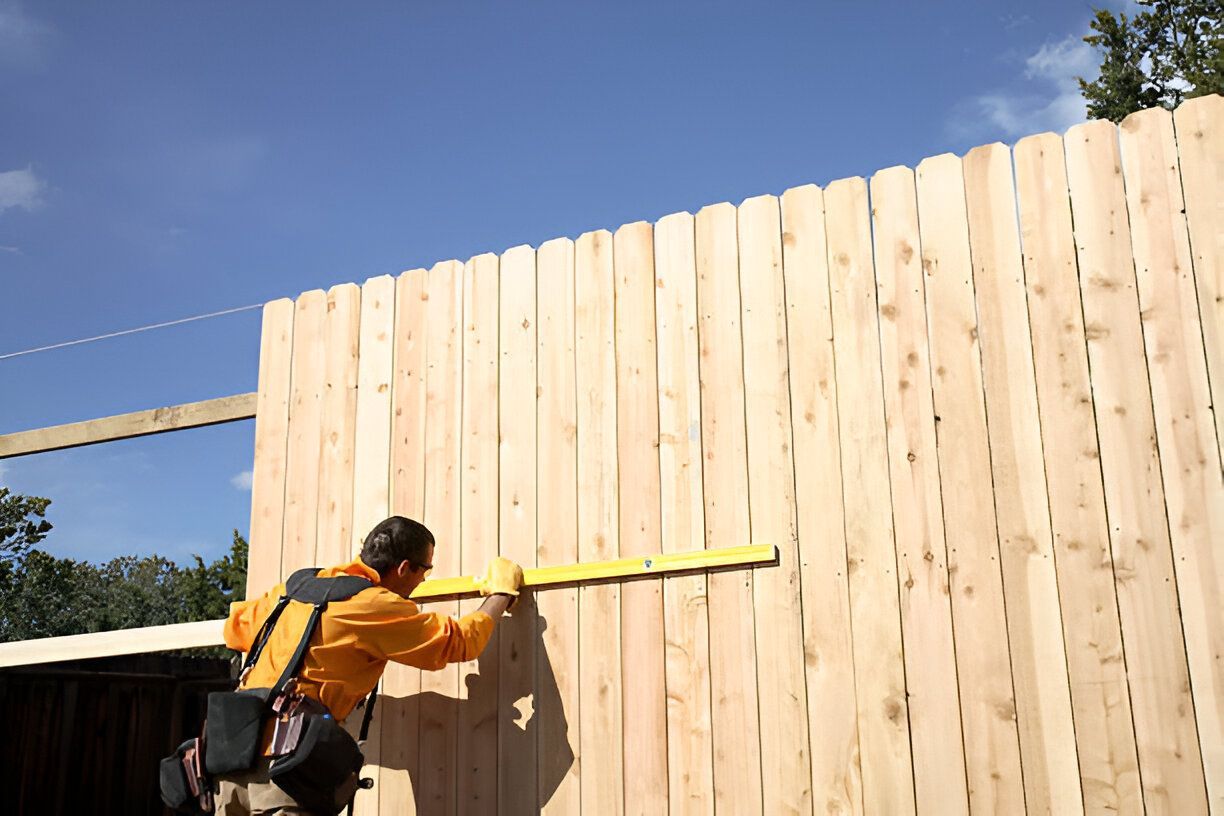 A contractor measures a wooden fence.
