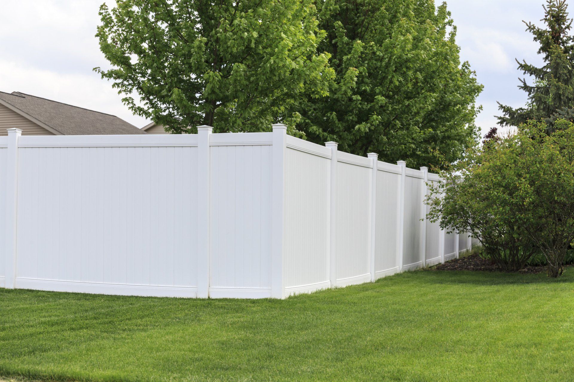A white fence surrounds a lush green yard.