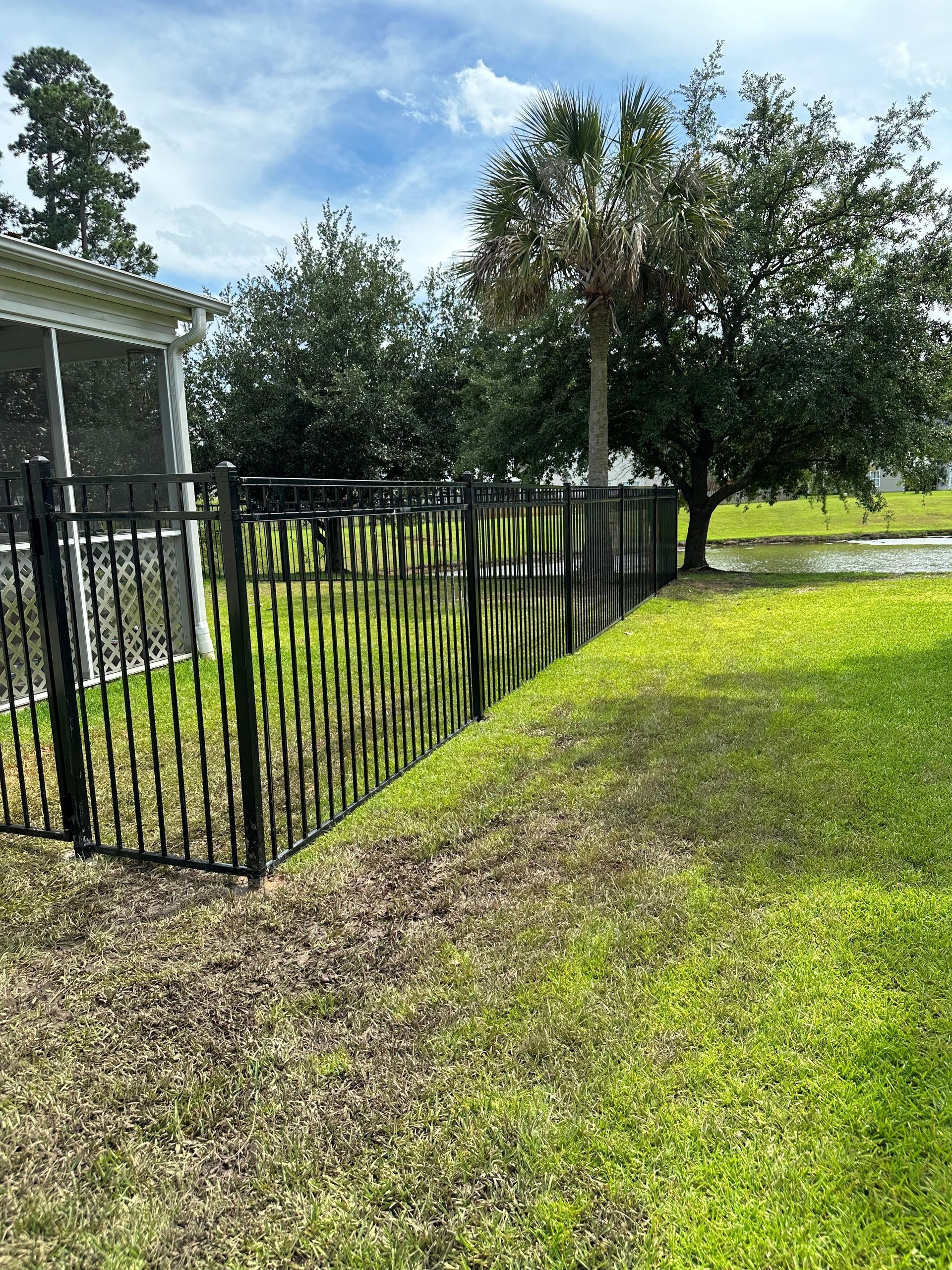 A black wrought iron fence surrounds a lush green yard.