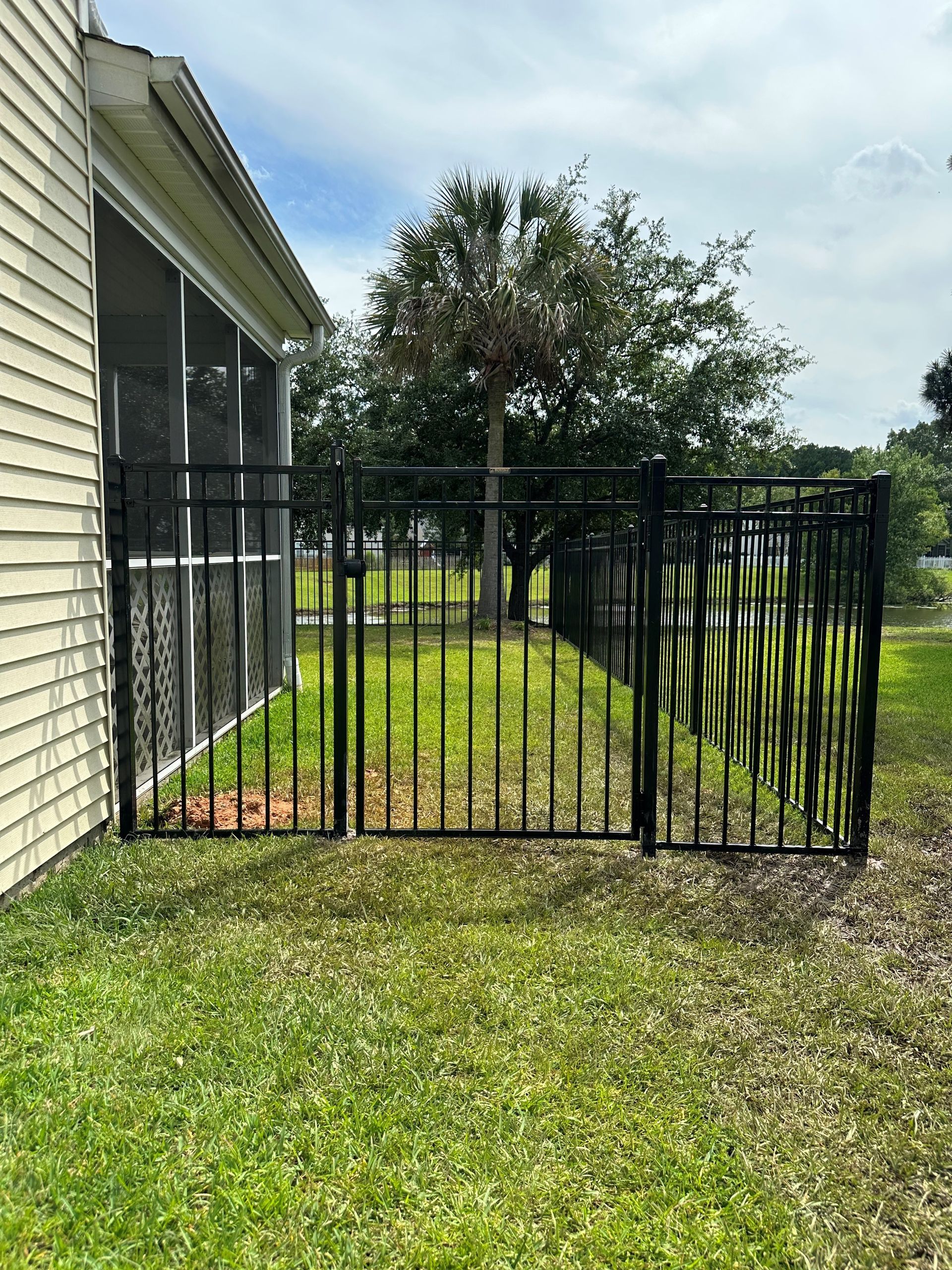 A black fence is sitting in front of a screened in porch.