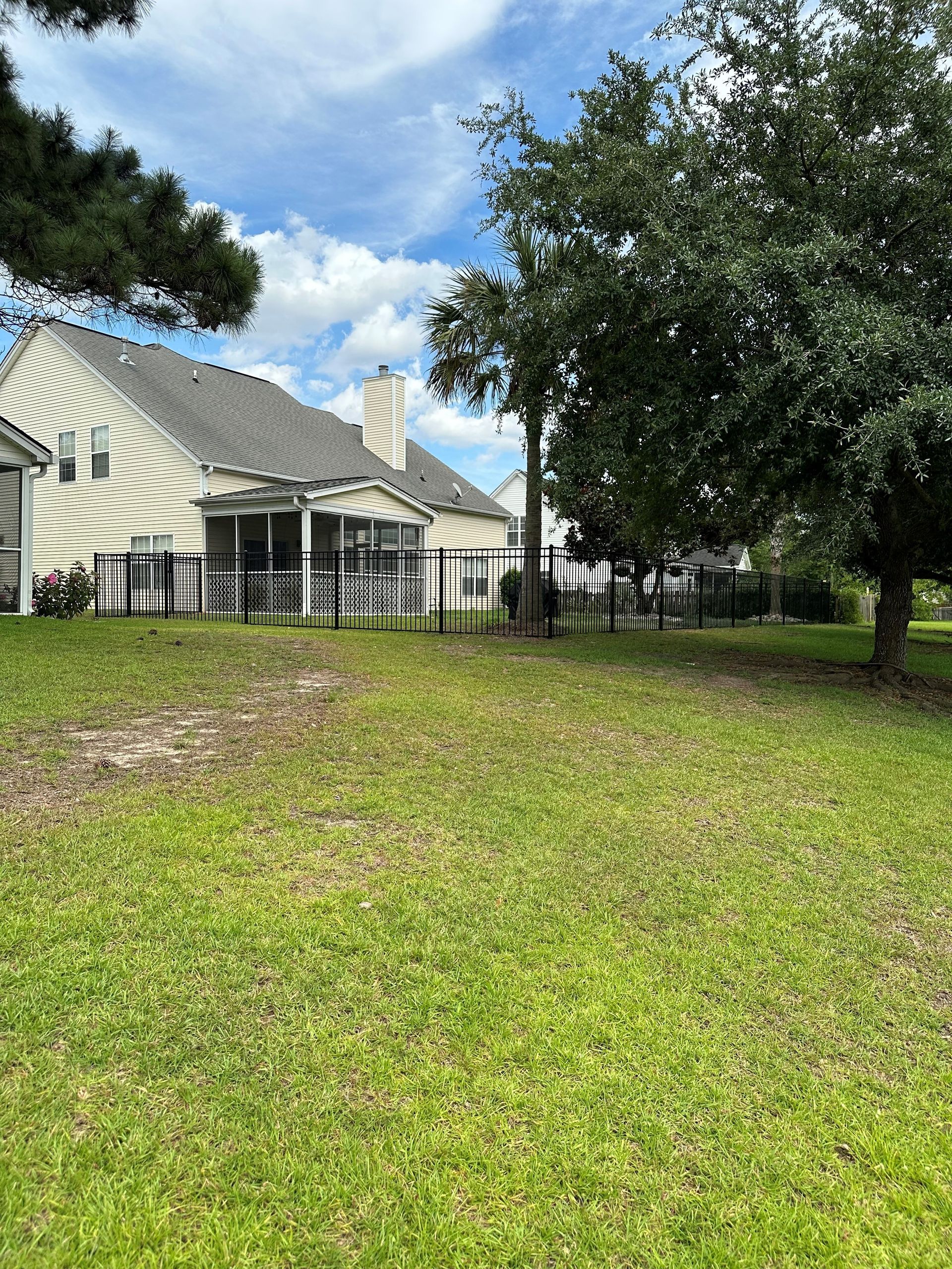 There is a house in the background and a fence in the foreground.