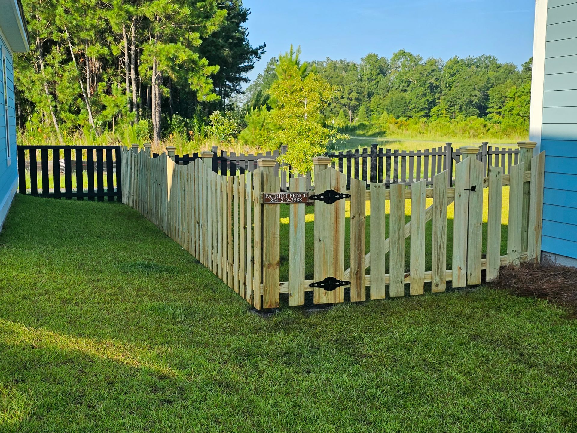 A wooden picket fence is in the backyard of a house.