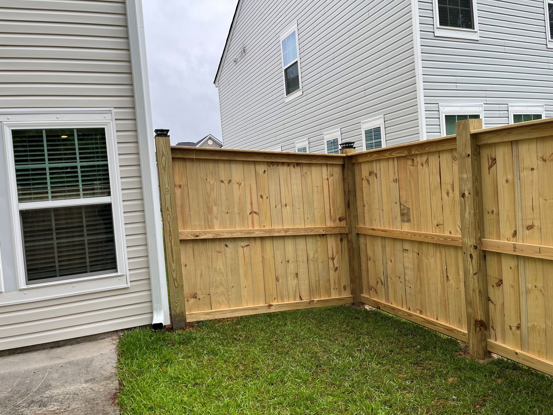 A wooden fence is in the backyard of a house.