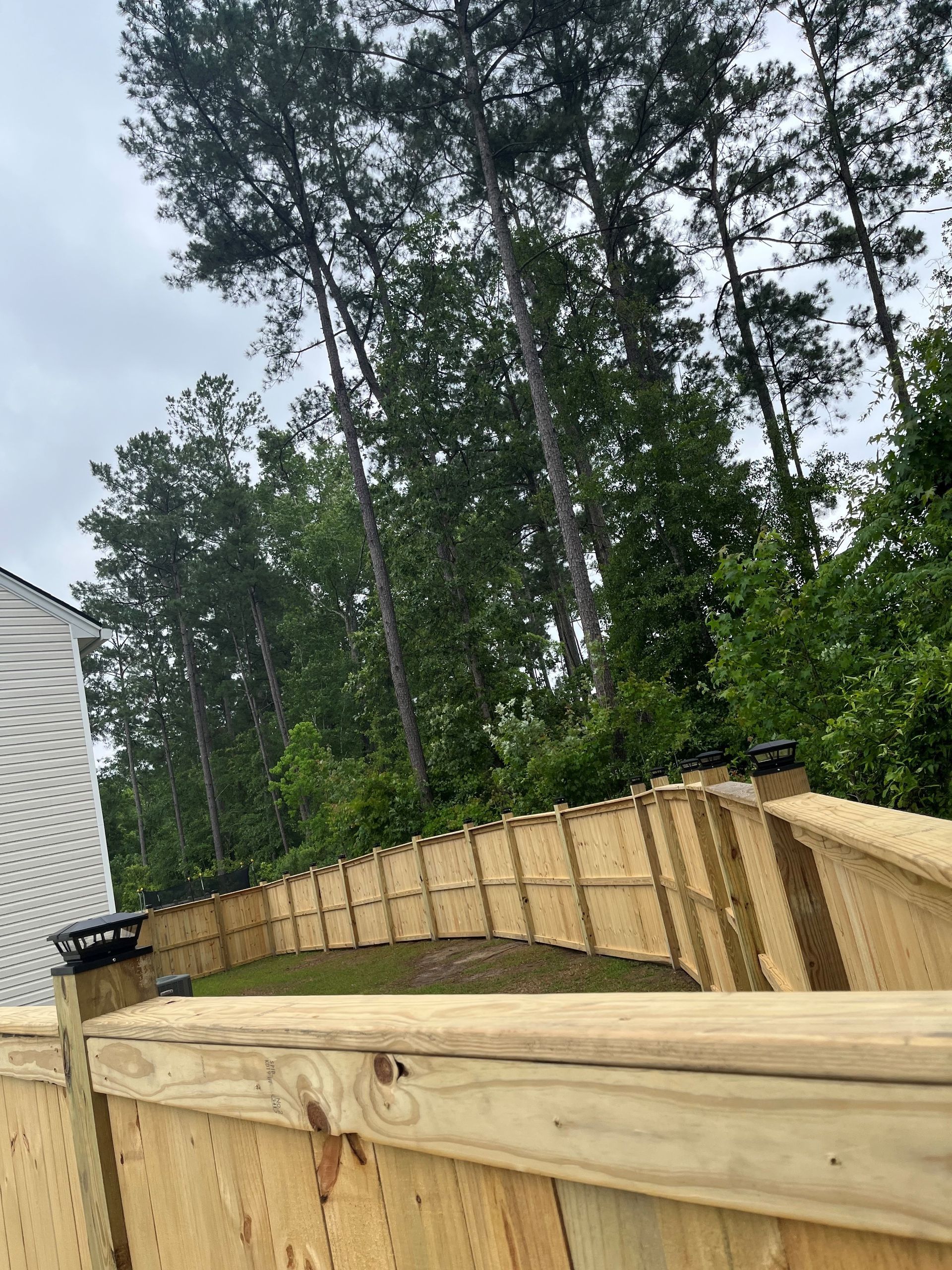 A wooden fence with trees in the background and a house in the background.