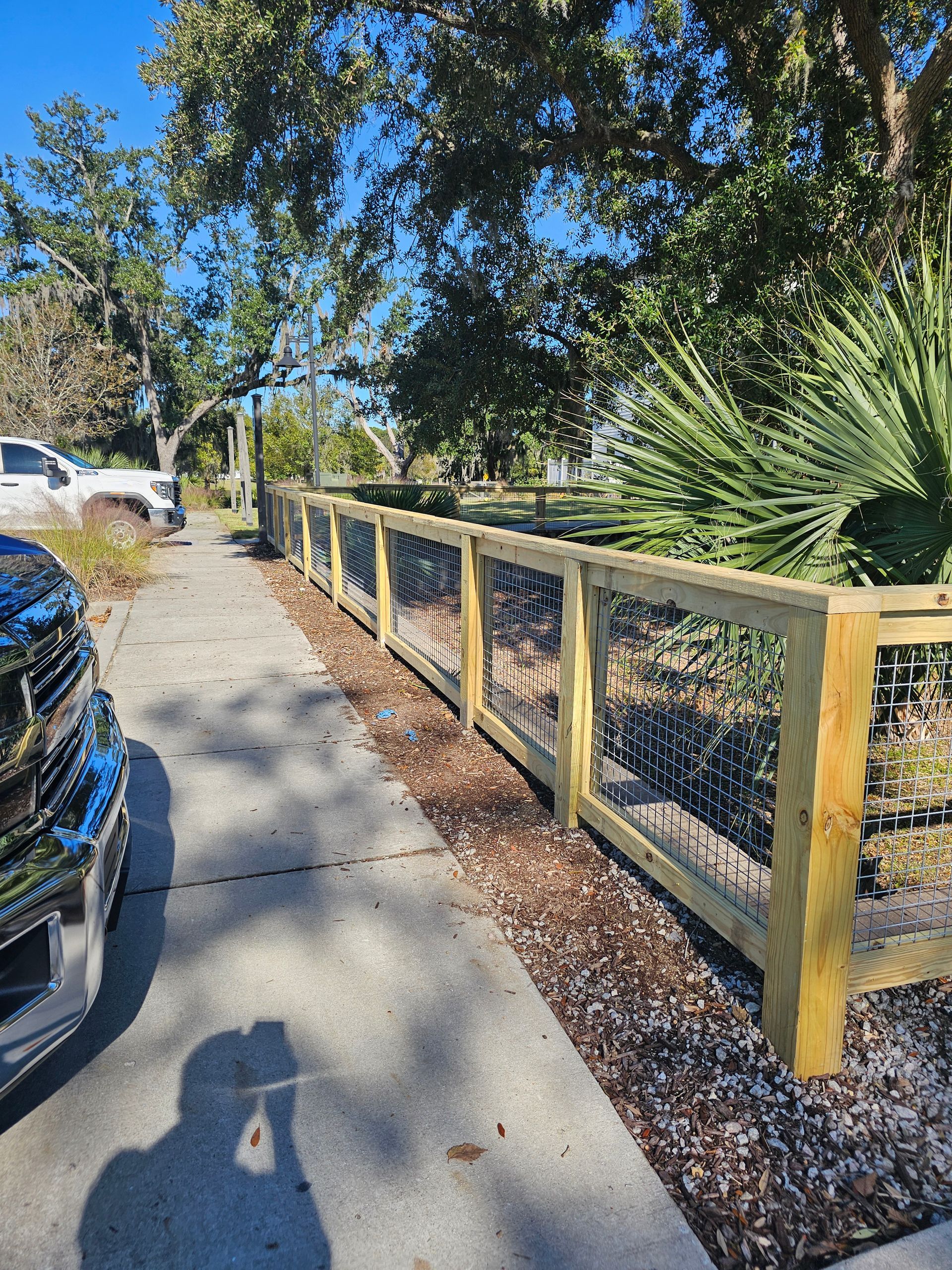 A truck is parked on the side of the road next to a wooden fence.