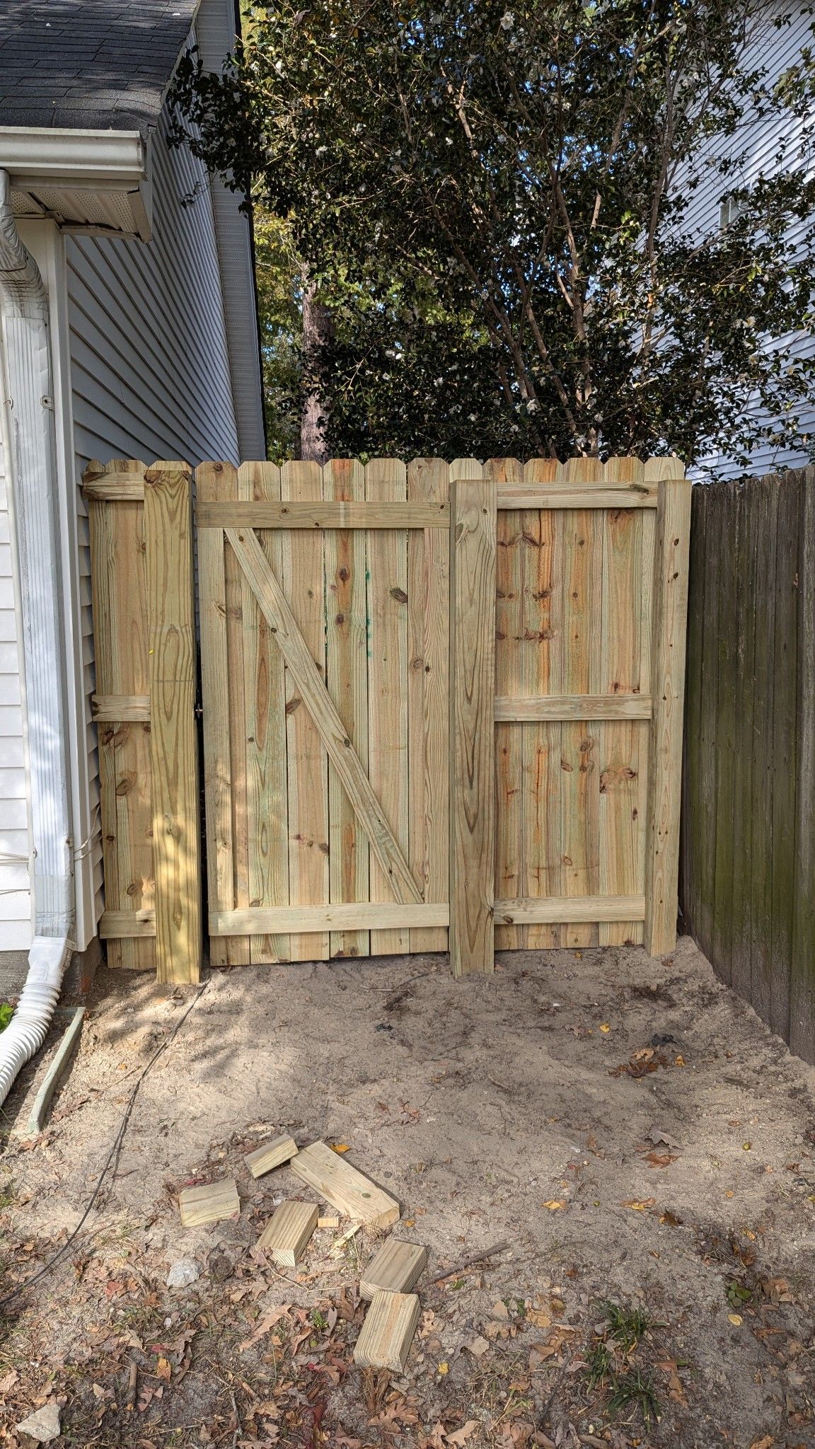 A wooden fence with a gate in the backyard of a house.