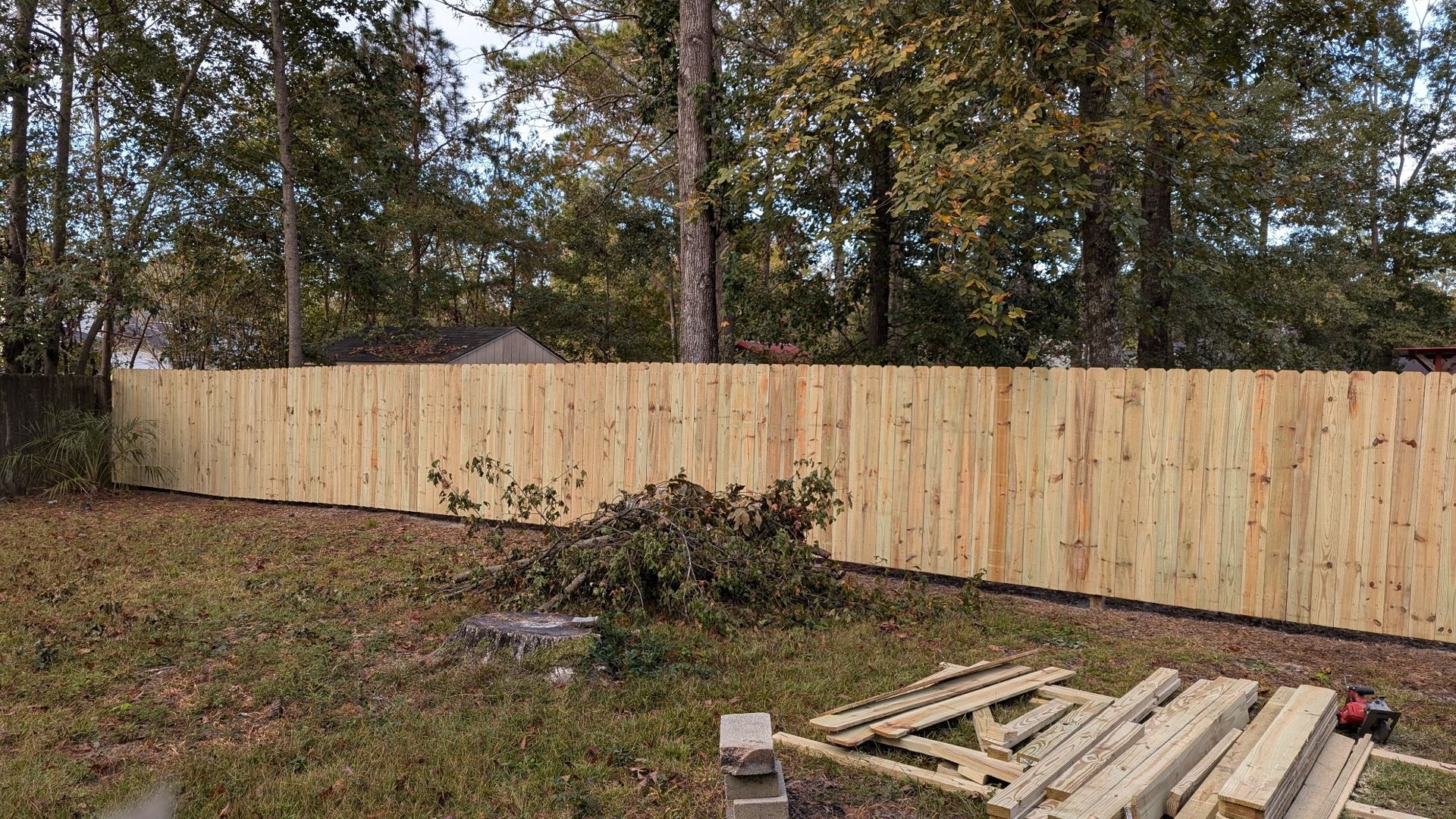 A wooden fence is being built in a backyard.