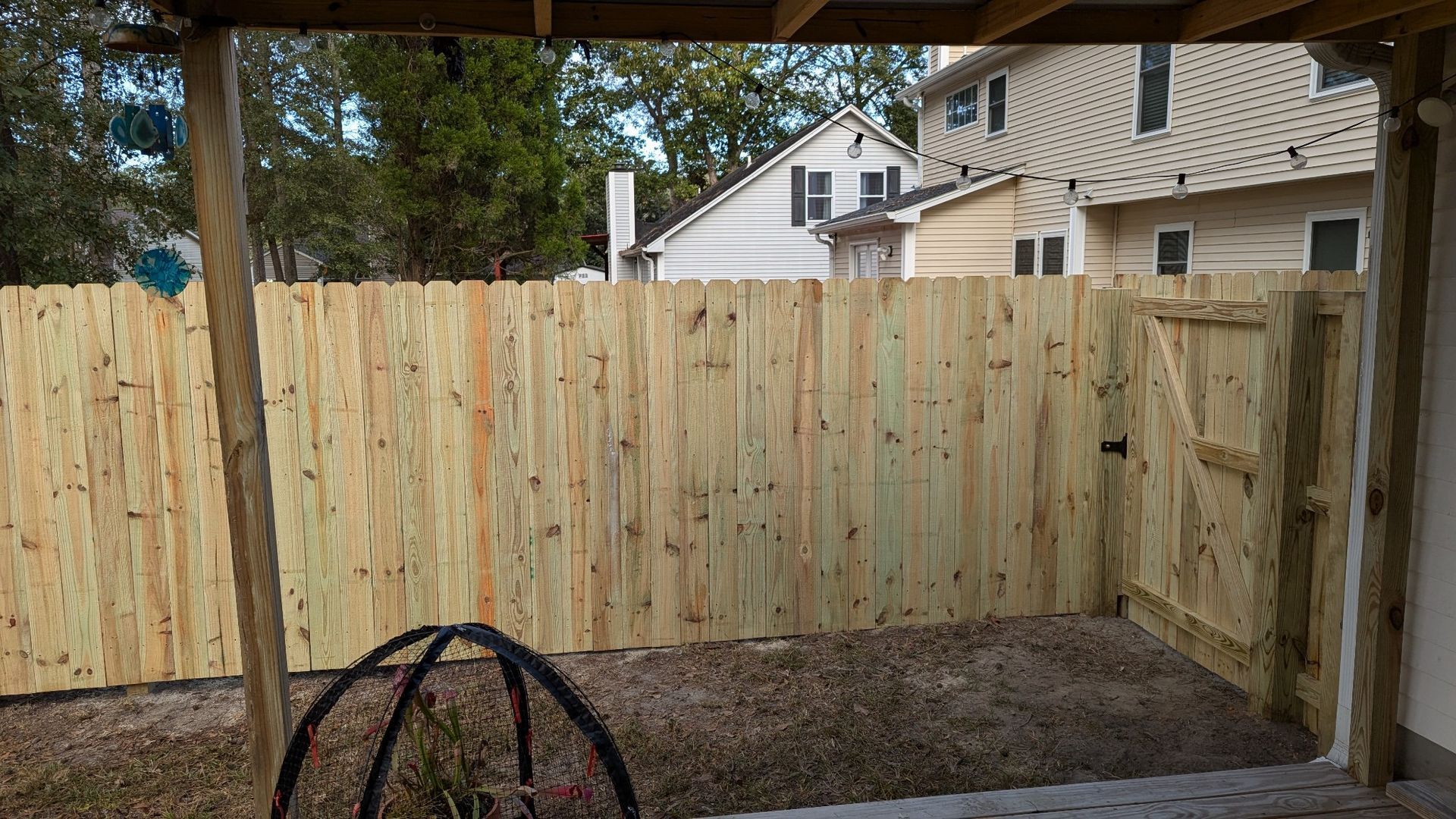 A wooden fence is in the backyard of a house.