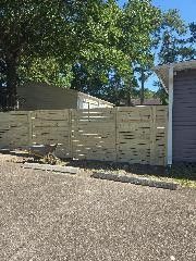 A wooden fence, installed by Patriot Fence Company, under the sun in front of a property.