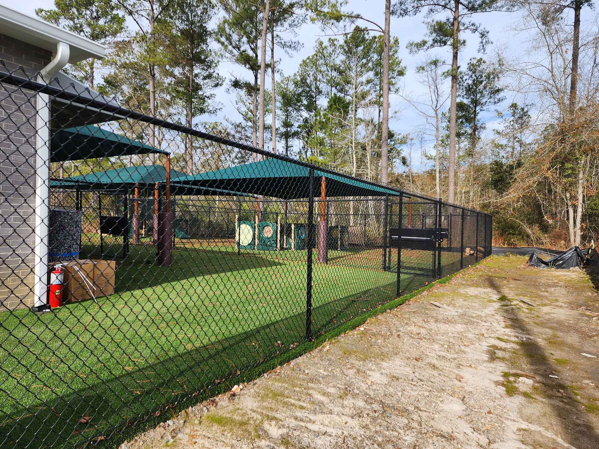 A chain link fence surrounds a playground in the woods.