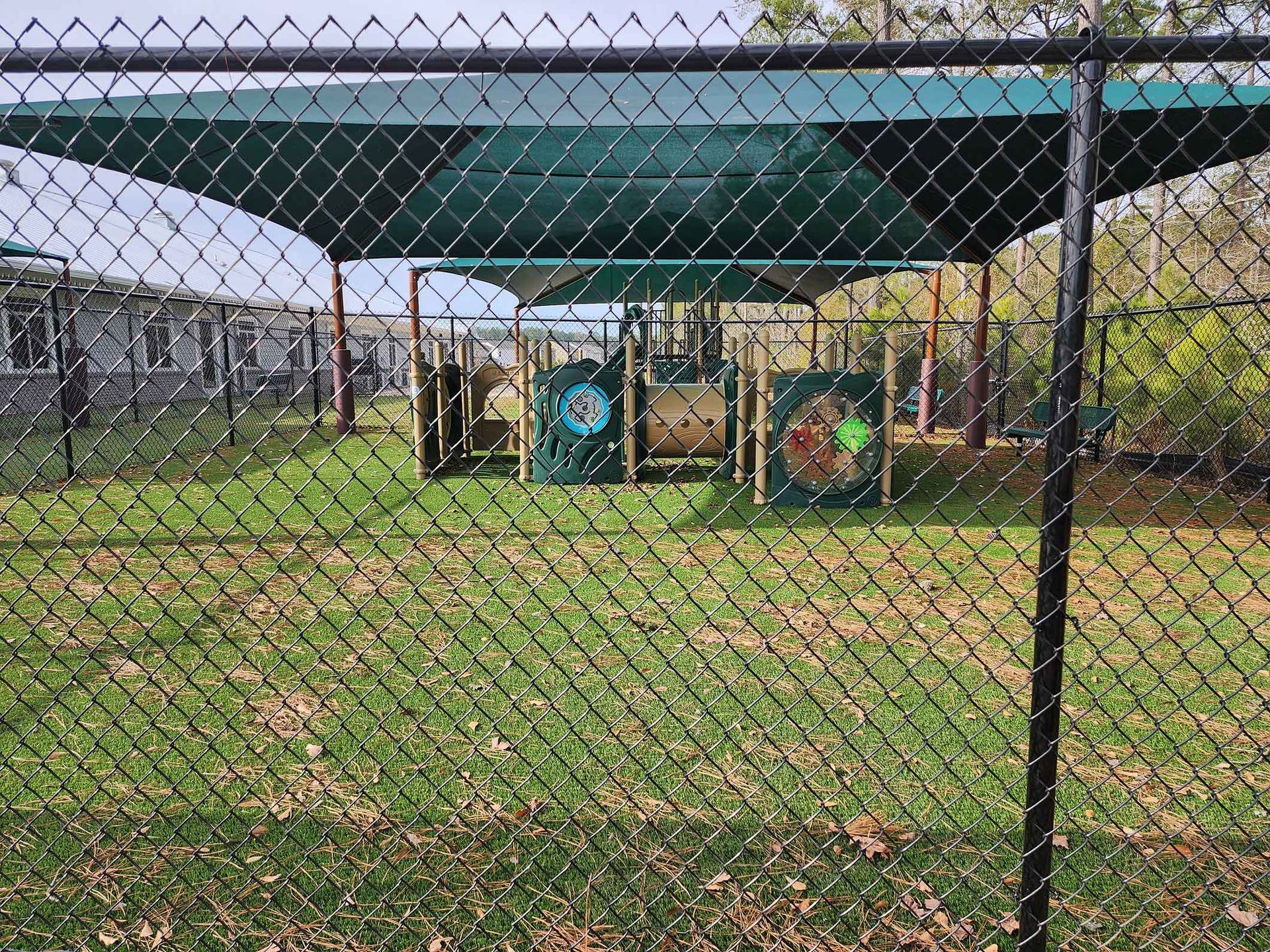 A chain link fence surrounds a playground in a park.