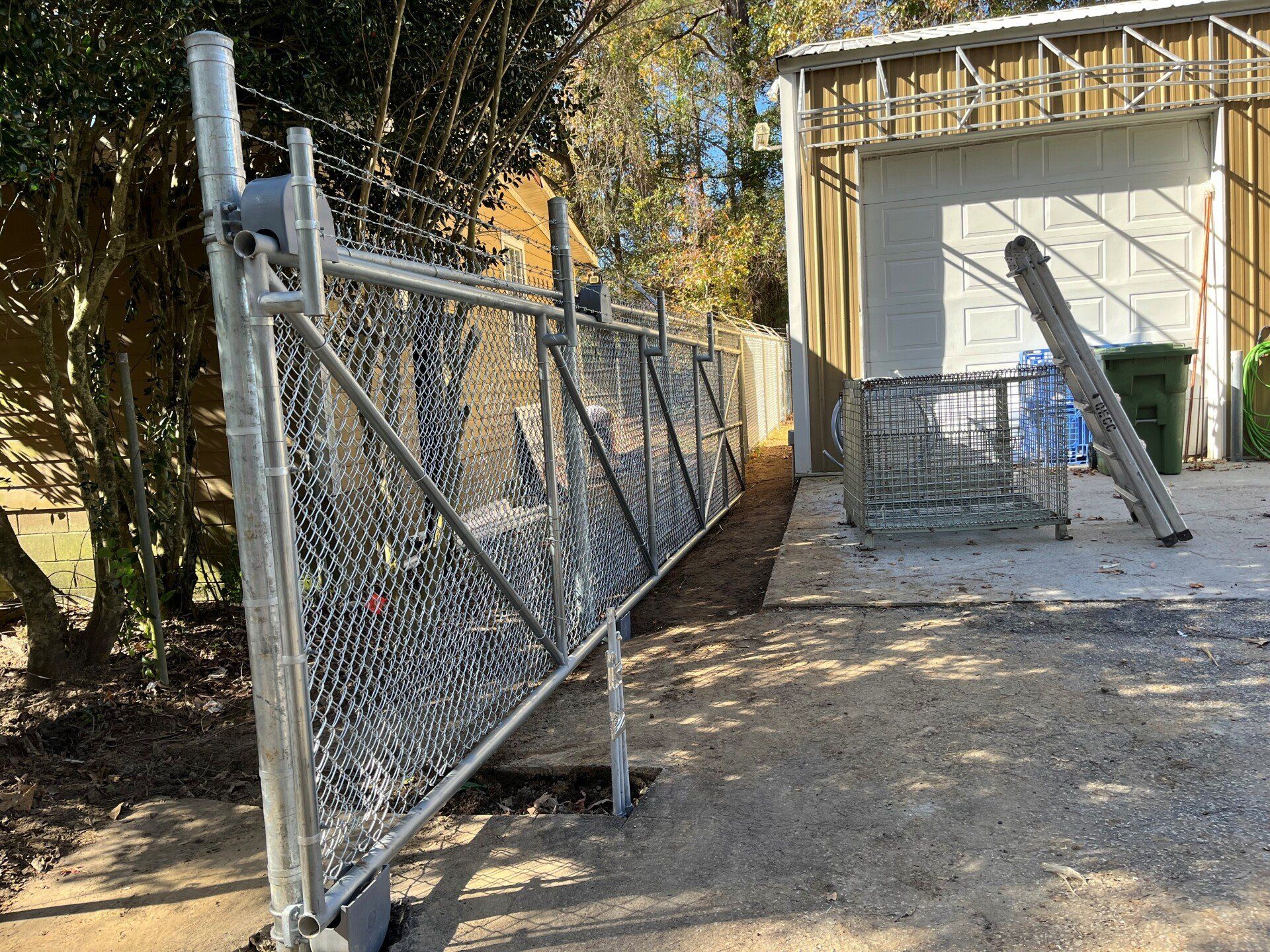 A chain link fence is being built in front of a garage.