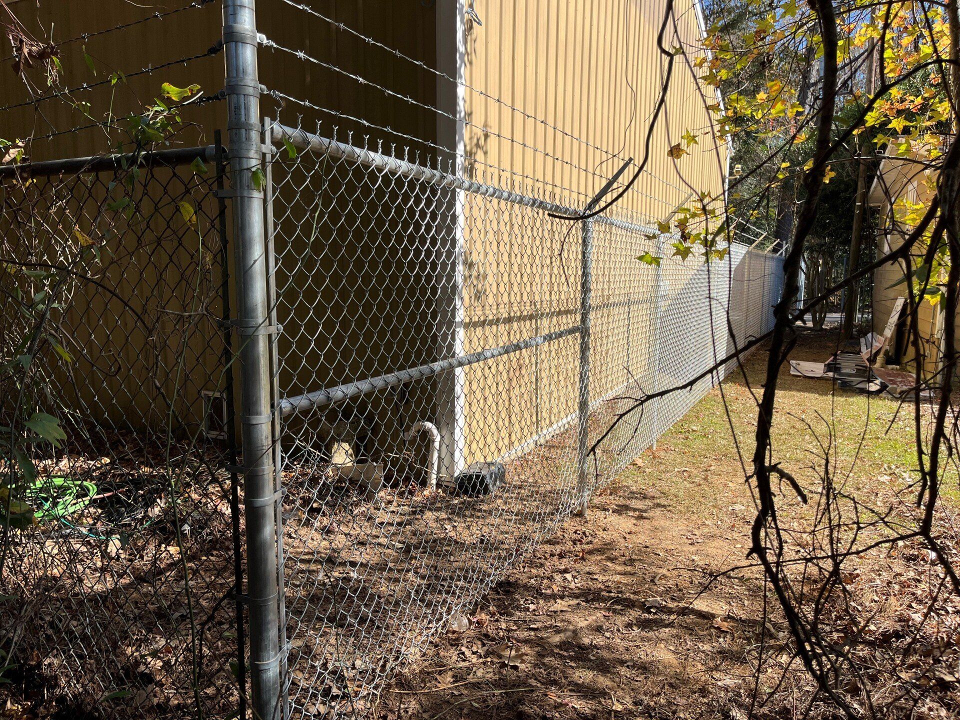A chain link fence is surrounding a building in the woods.