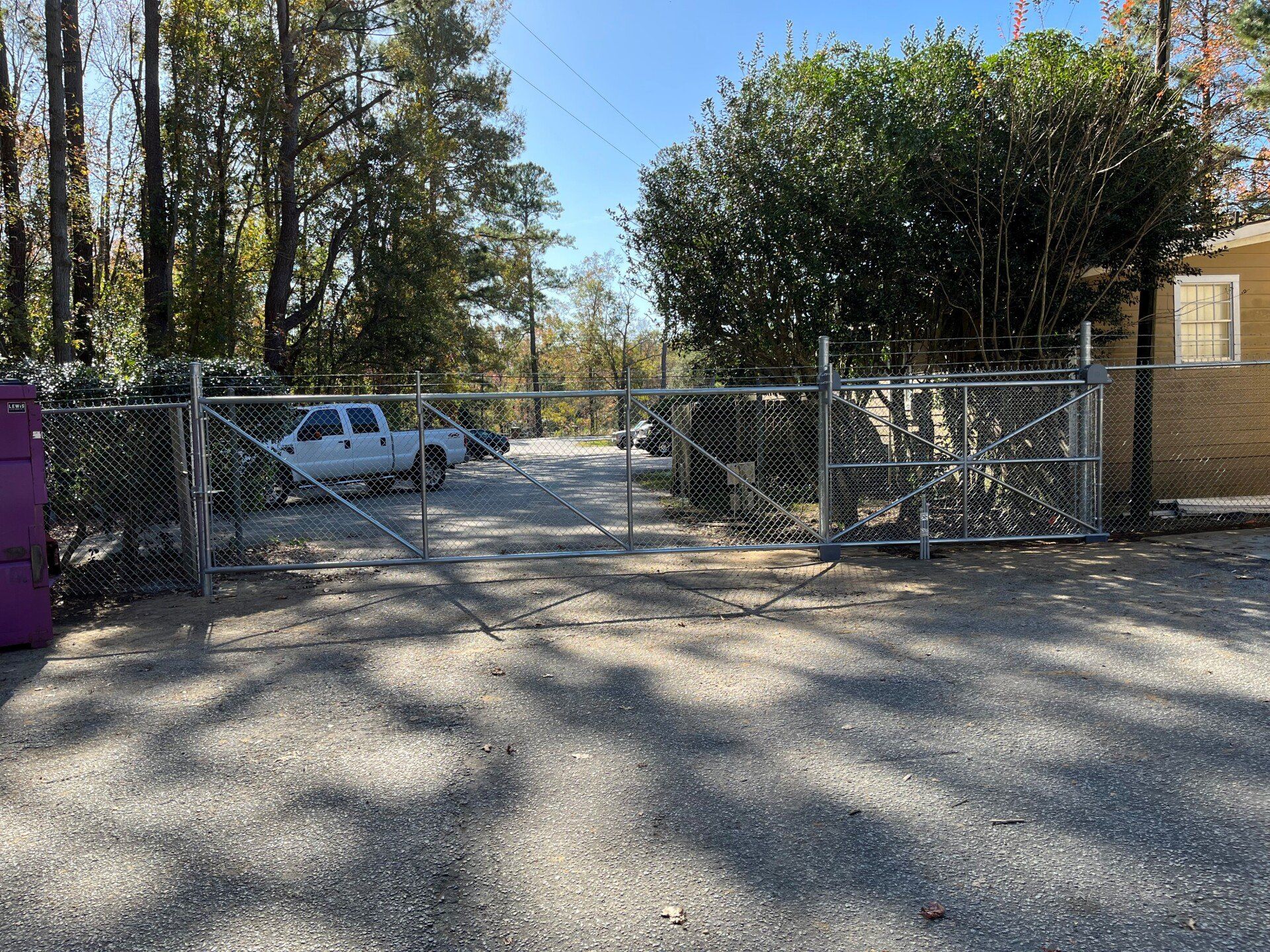 A white truck is parked in front of a chain link fence.