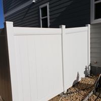 A white vinyl fence is sitting next to a house.