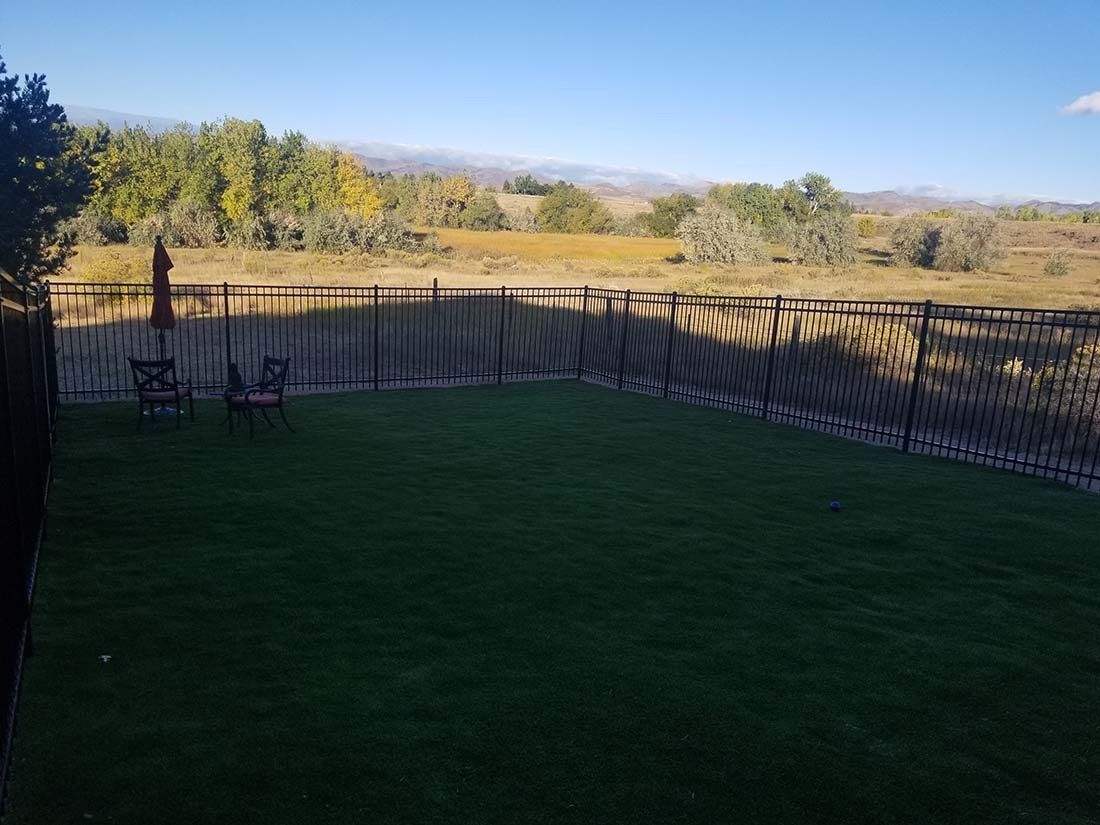A backyard with a fence and a view of a river.