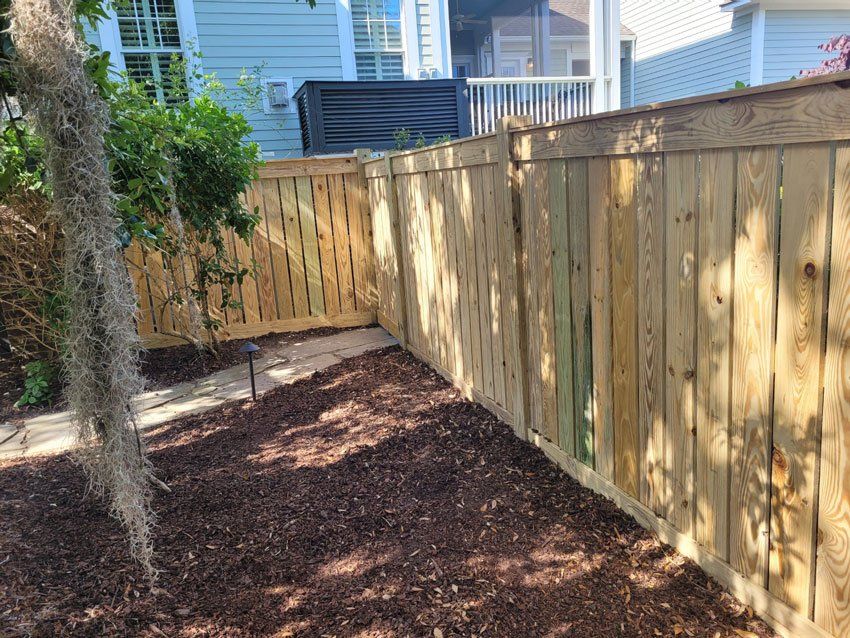 A wooden fence is in the backyard of a house.