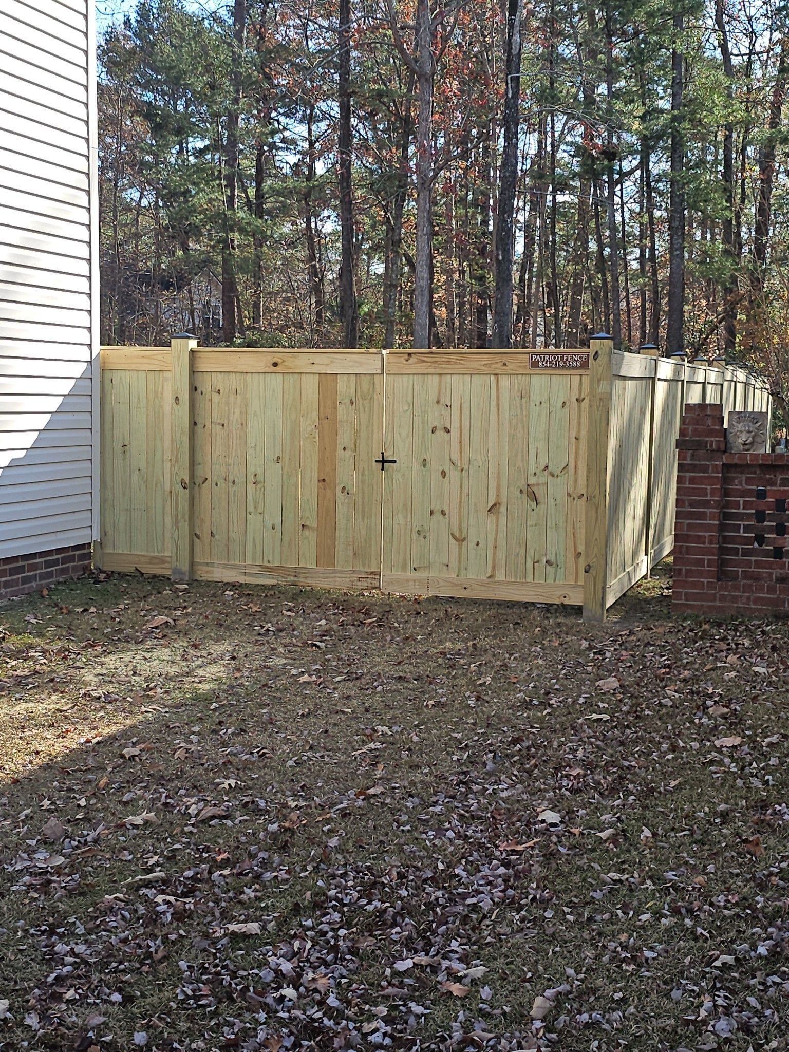 A wooden fence with a gate is in the backyard of a house.