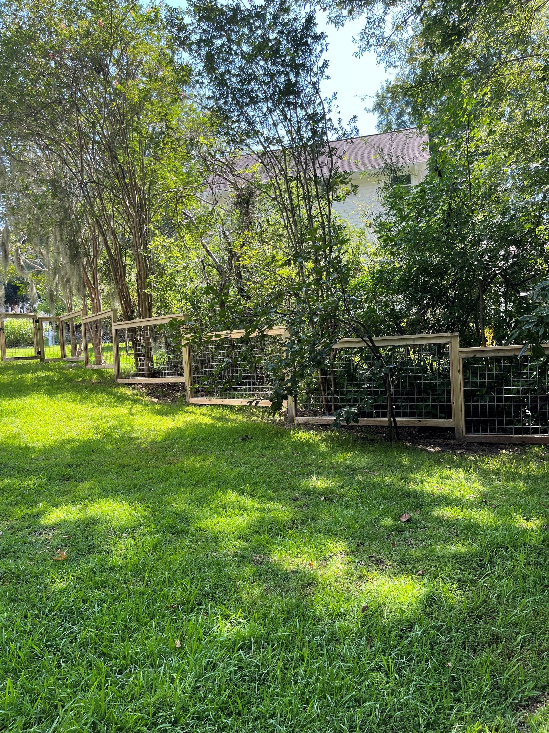 A wooden fence is in the middle of a lush green field.