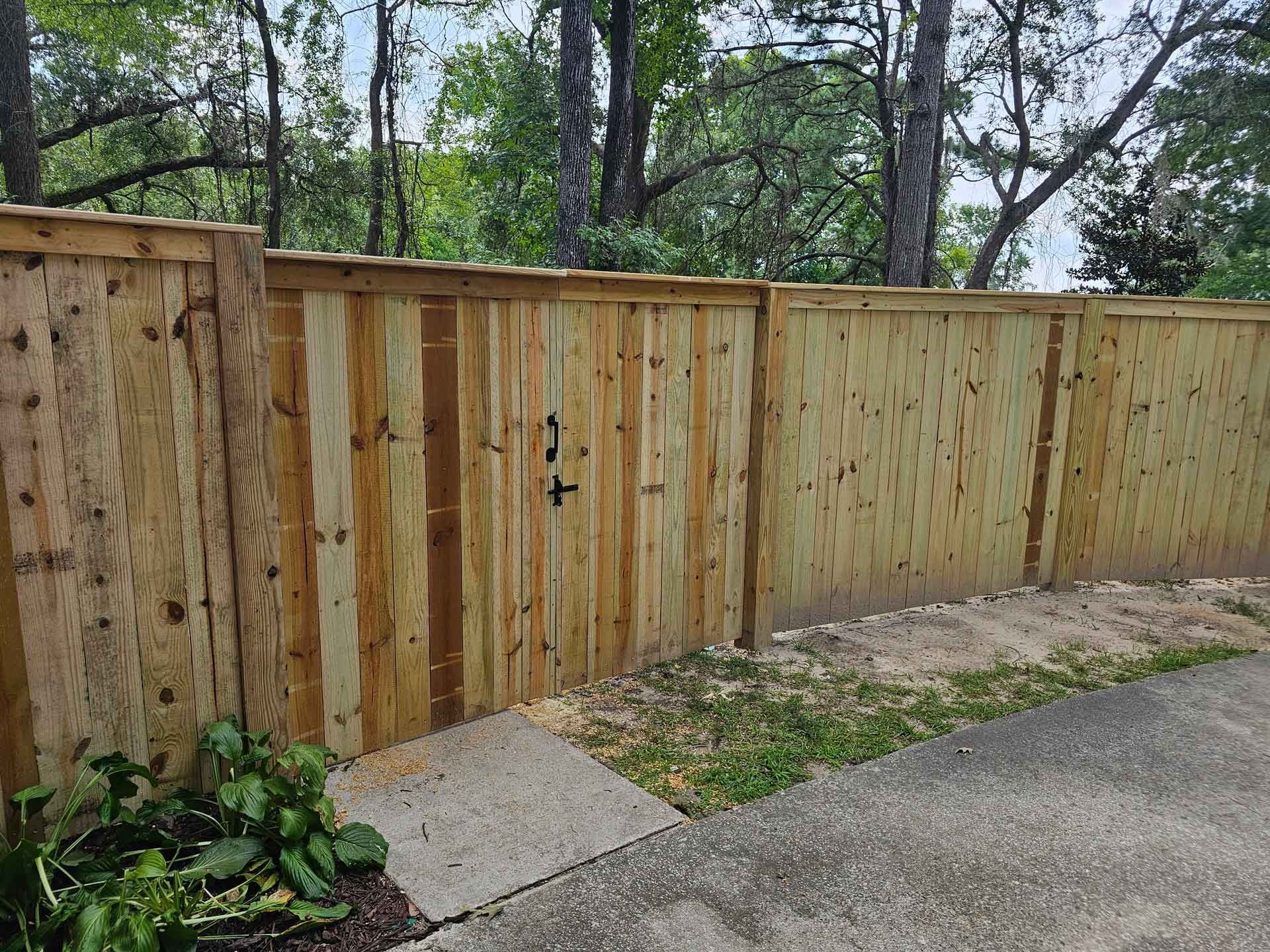 A wooden fence with a gate and trees in the background.