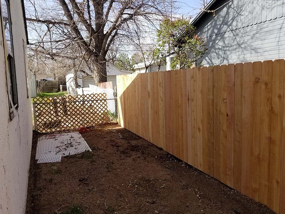 A wooden fence is in the backyard of a house.