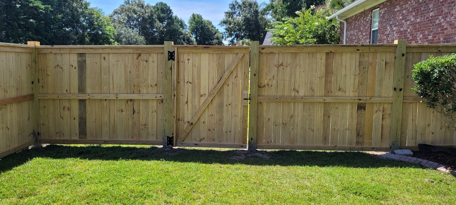 A wooden fence with a gate in the backyard of a house.